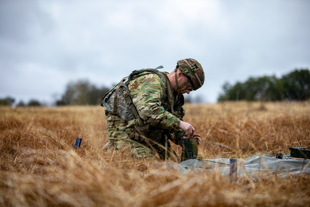 A solider assembles a radio in a field.