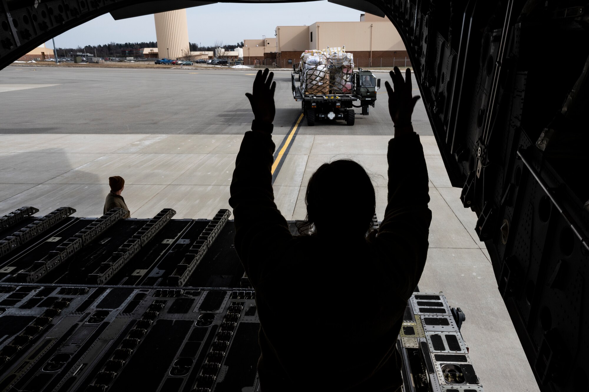 Senior Airman Josie Pitts, 758th Airlift Squadron loadmaster, directs an Airman assigned to the 32nd Aerial Port Squadron driving a 25K Halverson loader the Pittsburgh International Airport Air Reserve Station, Pennsylvania, Feb. 16, 2022.
