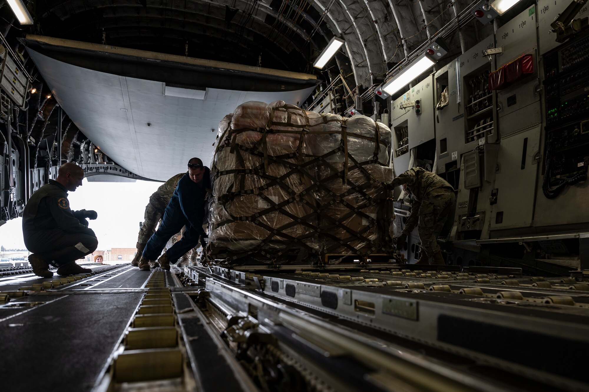 Airmen assigned to the 911th Airlift Wing load cargo for the Department of Defense's Denton Program onto a C-17 Globemaster III at the Pittsburgh International Airport Air Reserve Station, Pennsylvania, Feb. 16, 2022.