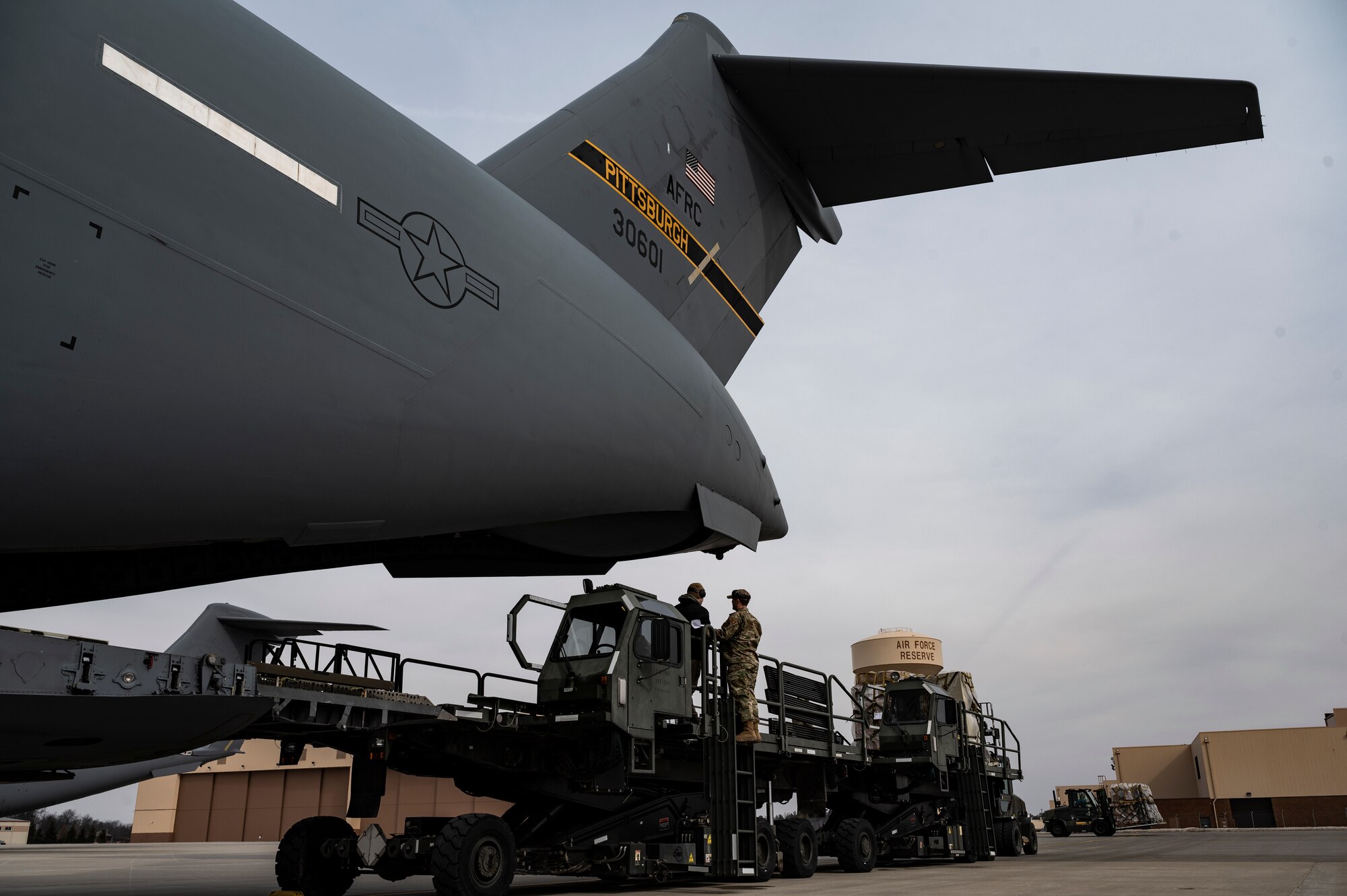 Airmen assigned to the 32nd Aerial Port Squadron discuss cargo loading information while loading cargo onto a C-17 Globemaster III at the Pittsburgh International Airport Air Reserve Station, Pennsylvania, Feb. 16, 2022.