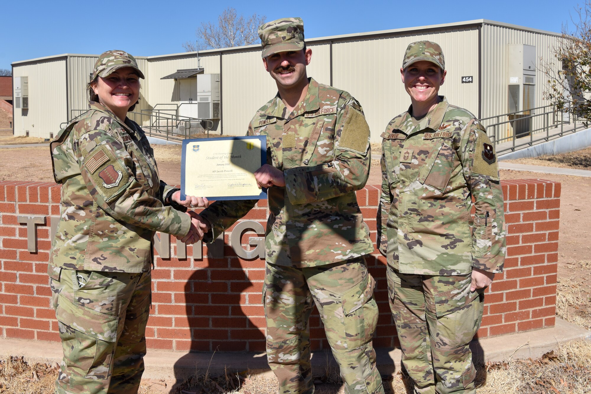 U.S. Air Force Col. Angelina Maguinness, 17th Training Group commander, and Chief Master Sgt. Breana Oliver, 17th TRG superintendent, presents Airman Jacob Powell, 312th Training Squadron student, a 17th TRG Student of the Month award for January 2022, outside of Brandenburg Hall, Goodfellow Air Force Base, Texas, Feb. 18, 2022. The 312th TRS’s mission is to train, develop, and inspire warriors to deliver Fire Emergency Services and Nuclear Treaty Monitoring for the Department of Defense. (U.S. Air Force photo by Staff Sgt. Jermaine Ayers)