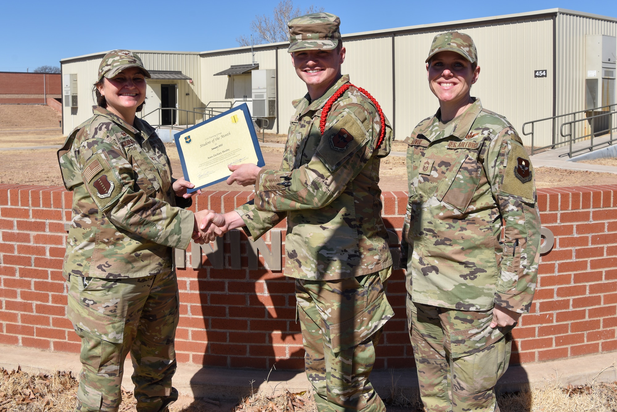 U.S. Air Force Col. Angelina Maguinness, 17th Training Group commander, and Chief Master Sgt. Breana Oliver, 17th TRG superintendent, presents Airman Zachary Henby, 315th Training Squadron student, a 17th TRG Student of the Month award for January 2022, outside of Brandenburg Hall, Goodfellow Air Force Base, Texas, Feb. 18, 2022. The 315th TRS’s mission is to train, educate and inspire the future intelligence, surveillance and reconnaissance warriors. (U.S. Air Force photo by Staff Sgt. Jermaine Ayers)