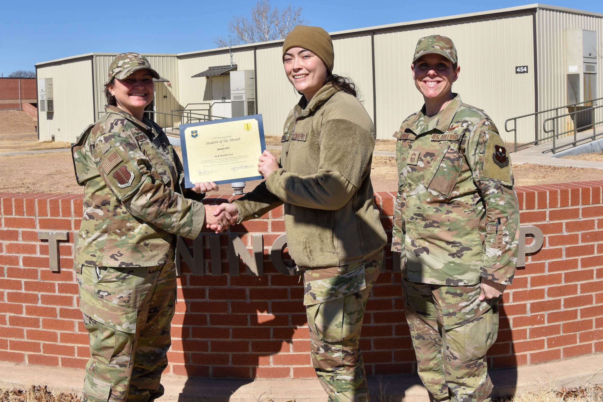 U.S. Air Force Col. Angelina Maguinness, 17th Training Group commander, and Chief Master Sgt. Breana Oliver, 17th TRG superintendent, presents Senior Airman Noelle Cyr, 316th Training Squadron student, a 17th TRG Student of the Month award for January 2022, outside of Brandenburg Hall, Goodfellow Air Force Base, Texas, Feb. 18, 2022. The 316th TRS is responsible for training, developing, and inspiring intelligence, surveillance and reconnaissance cryptologic leaders. (U.S. Air Force photo by Staff Sgt. Jermaine Ayers)