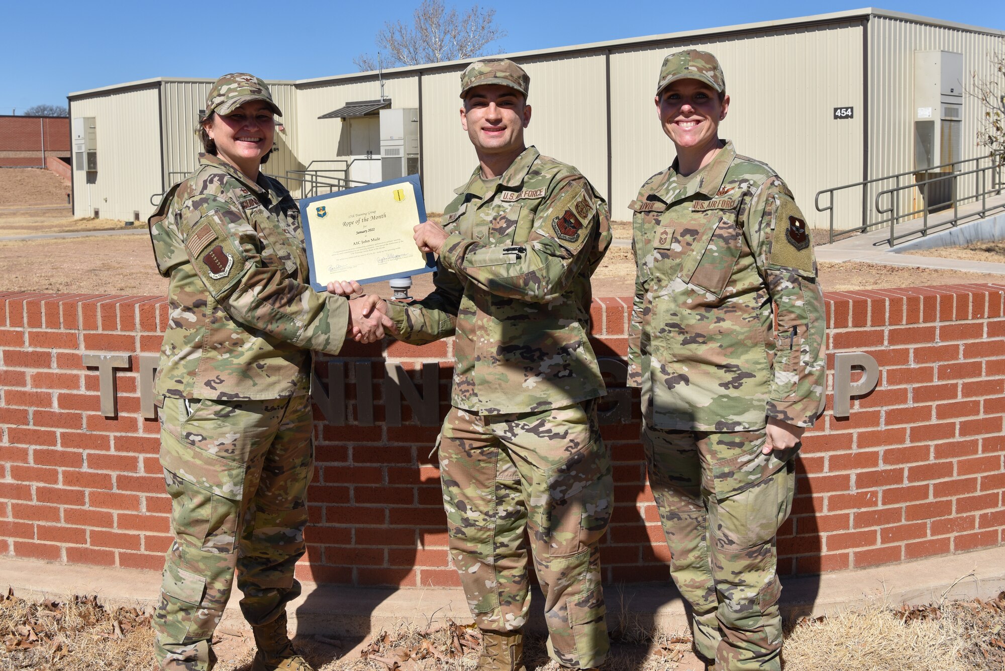 U.S. Air Force Col. Angelina Maguinness, 17th Training Group commander, and Chief Master Sgt. Breana Oliver, 17th TRG superintendent, presents Airman 1st Class John Mule, 312th Training Squadron student, the 17th TRG Rope of the Month award for January 2022, outside of Brandenburg Hall, Goodfellow Air Force Base, Texas, Feb. 18, 2022. Military Training Leaders present different ropes to Airmen who display exceptional qualities to lead their peers. Mule was recognized for his hard work and dedication in his rope duties. (U.S. Air Force photo by Staff Sgt. Jermaine Ayers)