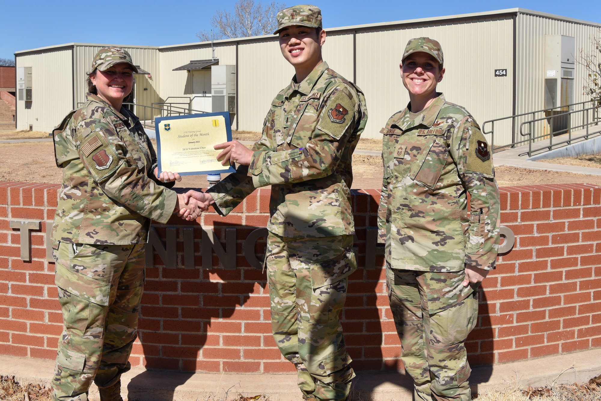 U.S. Air Force Col. Angelina Maguinness, 17th Training Group commander, and Chief Master Sgt. Breana Oliver, 17th TRG superintendent, presents 2nd Lt. Valentine Chan, 315th Training Squadron student, a 17th TRG Student of the Month award for January 2022, outside of Brandenburg Hall, Goodfellow Air Force Base, Texas, Feb. 18, 2022. Chan worked hard for his award and has shown his dedication to his squadron and the training he received at Goodfellow. (U.S. Air Force photo by Staff Sgt. Jermaine Ayers)