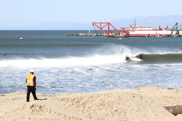 A contractor surveys the area before dredging operations start Feb. 17 in Ventura Harbor. Though parts of the beach adjacent to the project are available for recreation -- such as surfing visible in this photo -- large sections of the beach are strictly off-limits to ensure the safety of residents and visitors.