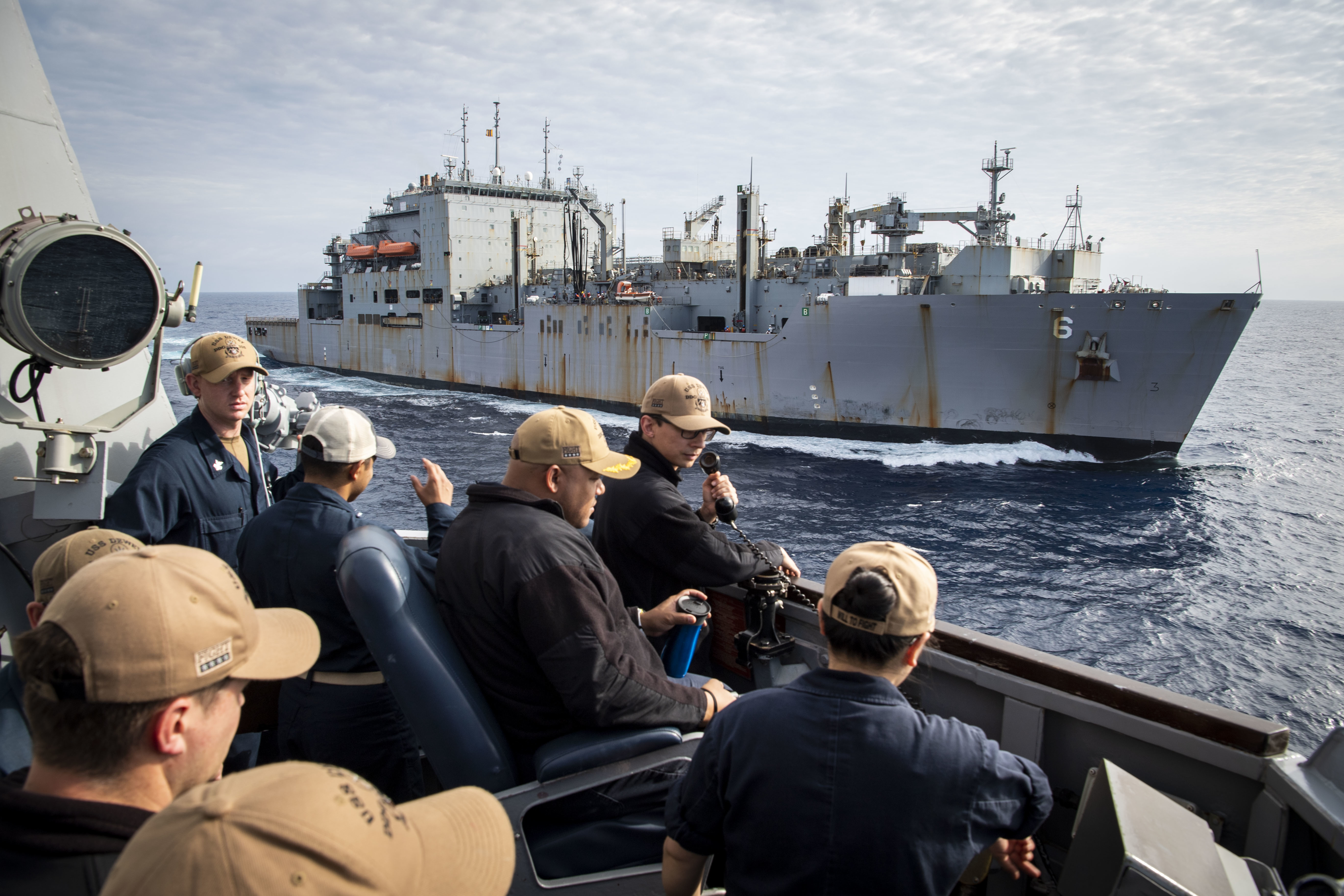 Cmdr. Jermaine Brooms, center, commanding officer of USS Dewey (DDG 105), supervises maneuvering from the bridge wing following a replenishment-at-sea with USNS Amelia Earhart (T-AKE 6).