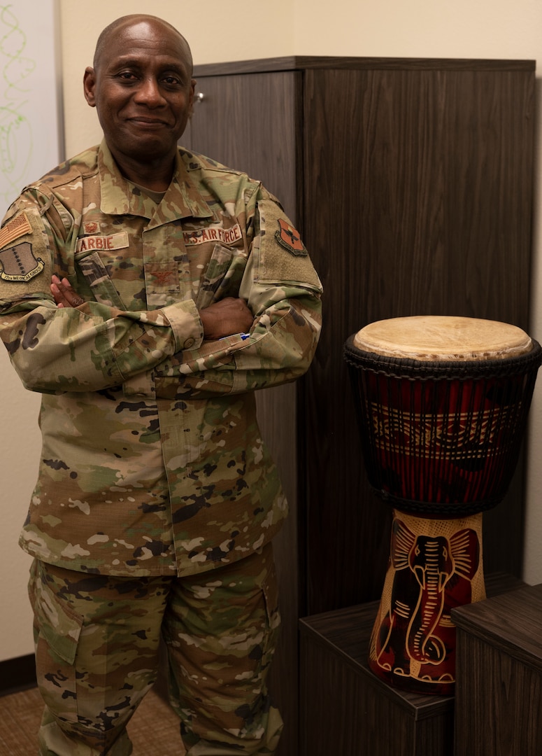 U.S. Air Force Col. Derek Larbie, 17th Medical Group commander, poses next to an African drum at the Ross Clinic, Goodfellow Air Force Base, Texas, Feb. 17, 2022. This drum is one of many pieces of memorabilia Larbie has brought from his home country of Ghana. (U.S. Air Force photo by, Senior Airman Michael Bowman)