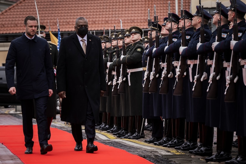 Secretary of Defense Lloyd J. Austin III and Lithuanian Acting Minister of Defense Garbrielius Landsbergis walk on a red carpet near troops.