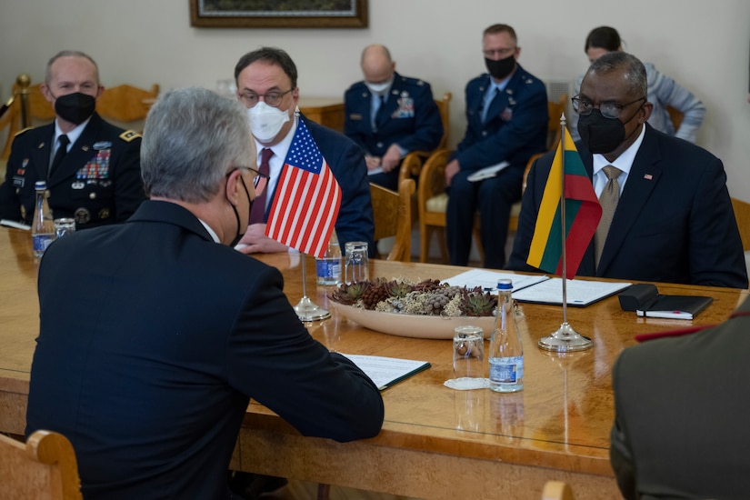 Men wearing mask sit at a conference table.