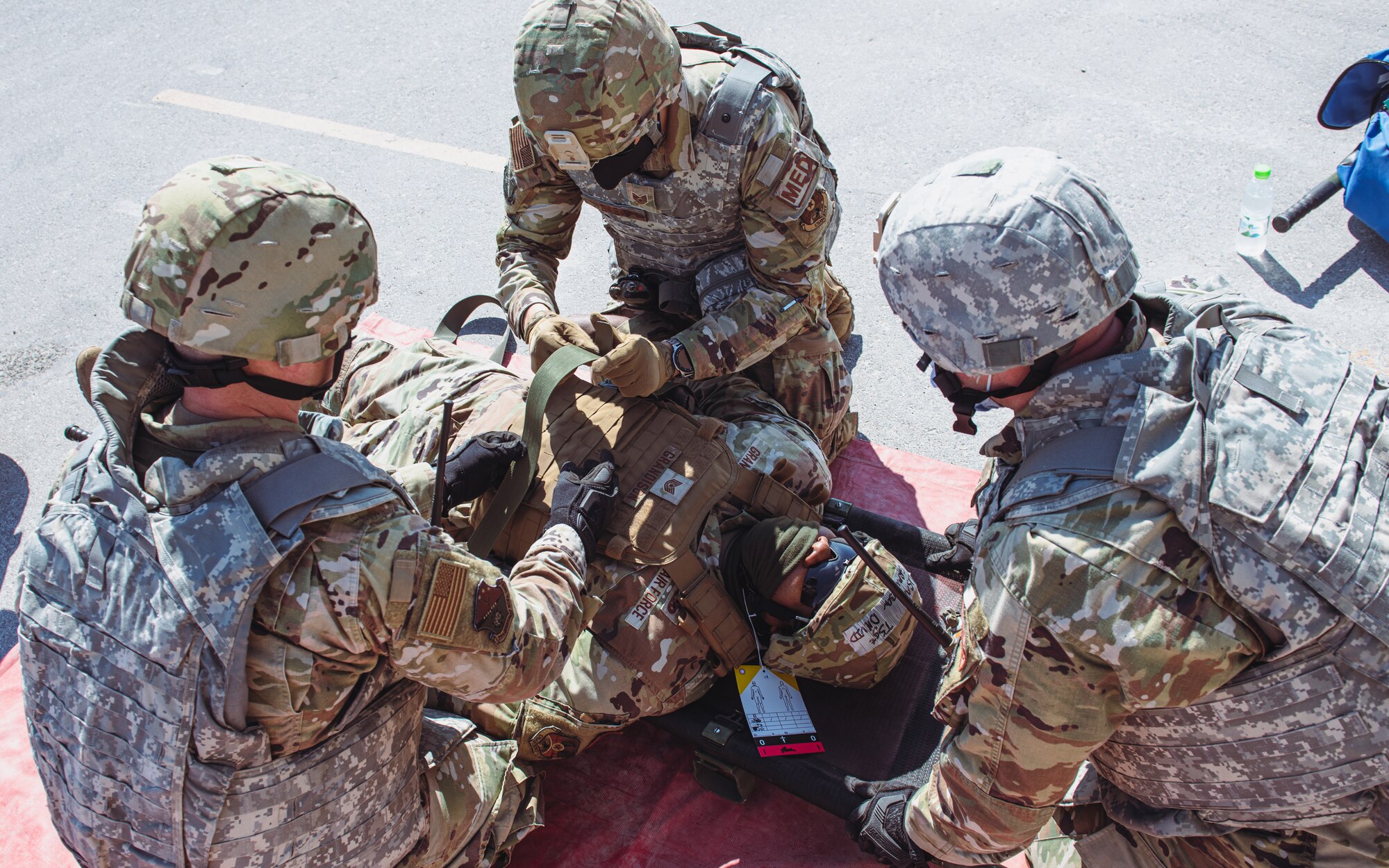 Airmen secure patient to a stretcher.