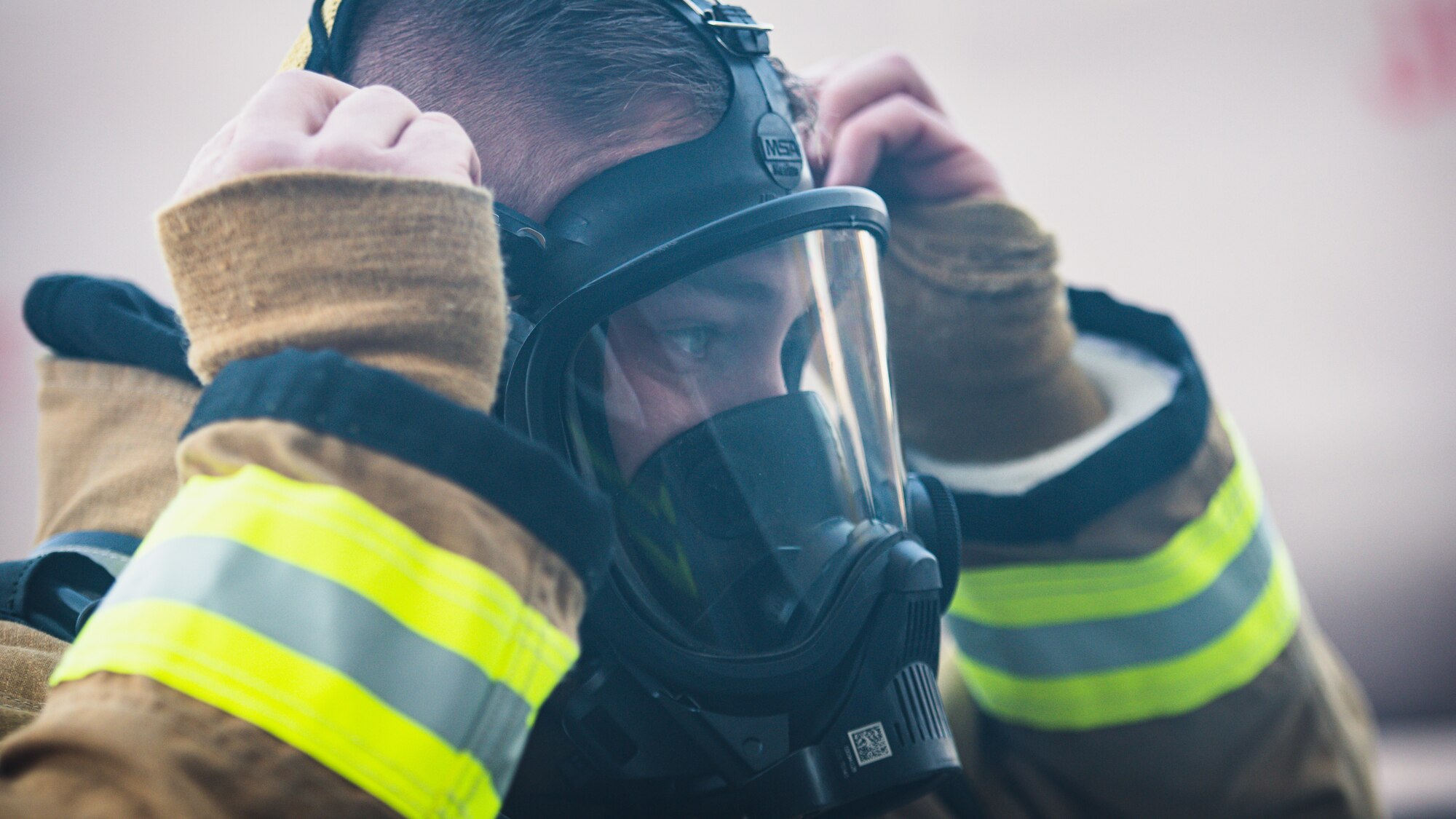 Firefighter puts on gas mask.