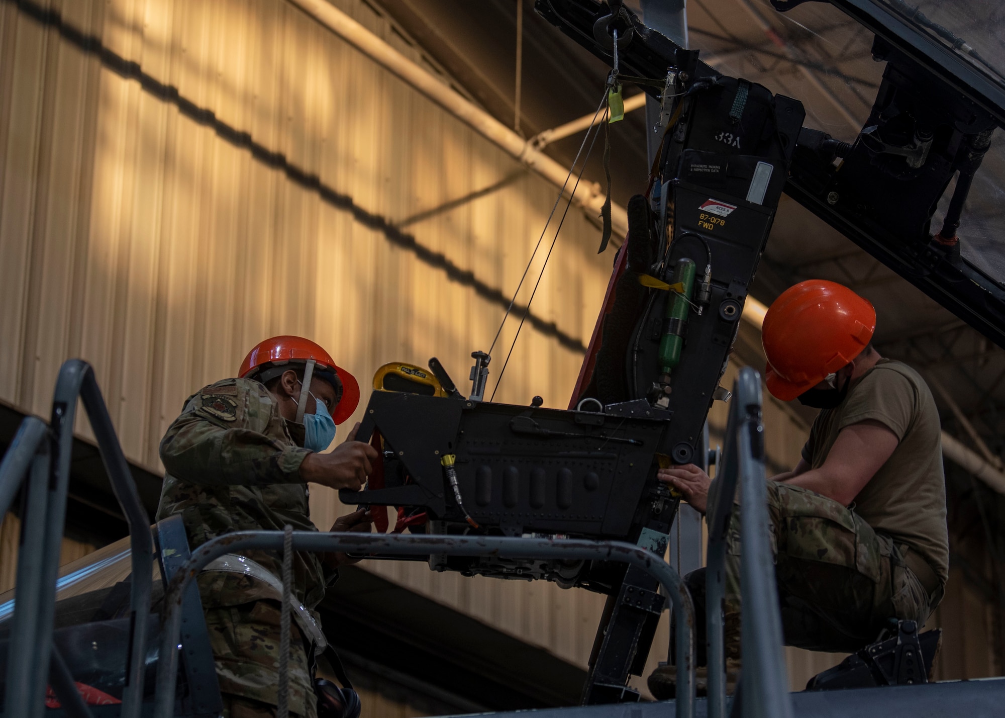 Airman 1st Class Latrell Blackwell, left, and Senior Airman Kyle Hogan, 4th Component Maintenance Squadron aircrew egress technicians, install an ejection seat into an F-15E Strike Eagle at Seymour Johnson Air Force Base, North Carolina, Jan. 7, 2022.