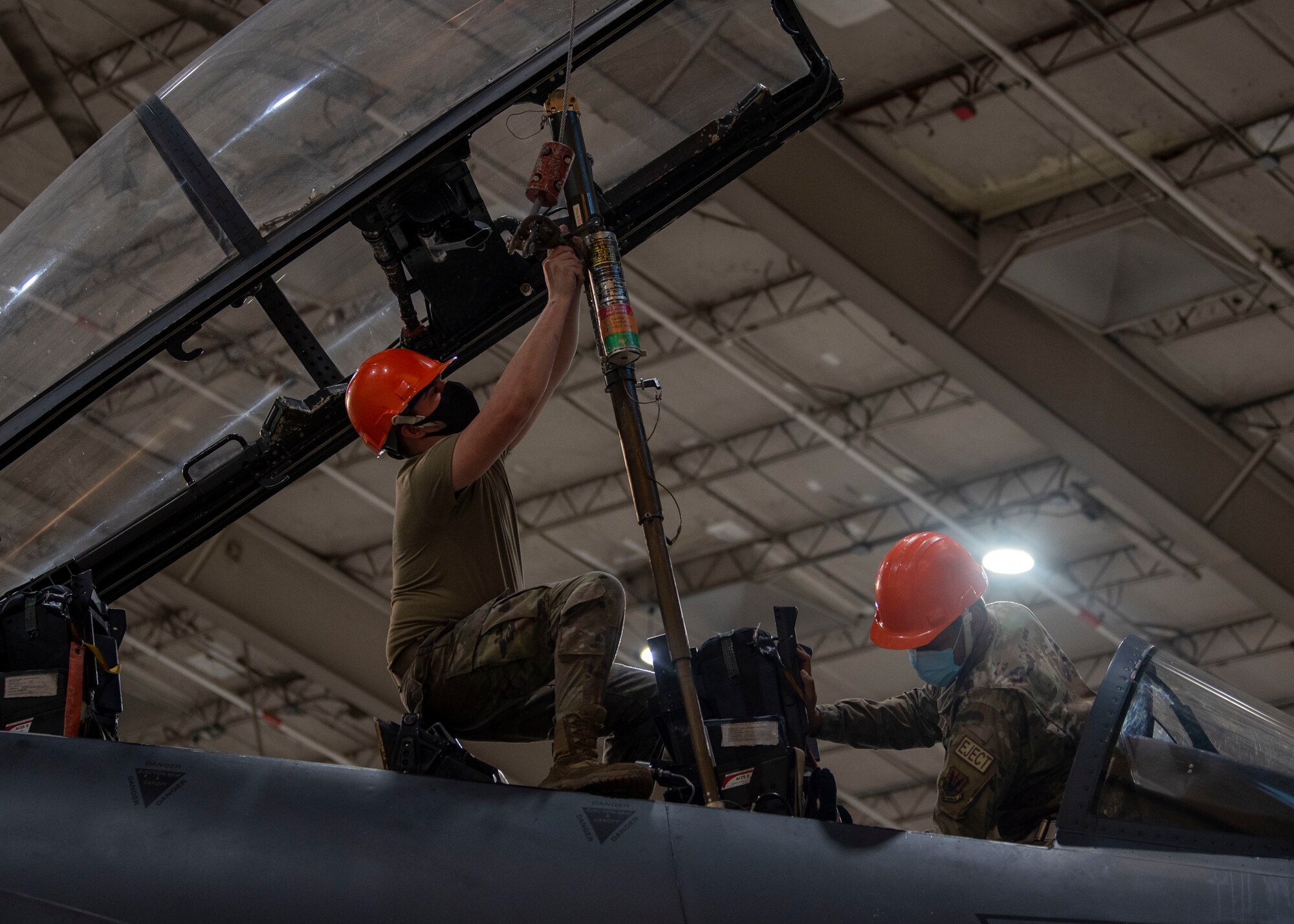 Senior Airman Kyle Hogan, left, and Airman 1st Class Latrell Blackwell, 4th Component Maintenance Squadron aircrew egress technicians, install an ejection seat into an F-15E Strike Eagle at Seymour Johnson Air Force Base, North Carolina, Jan. 7, 2022.