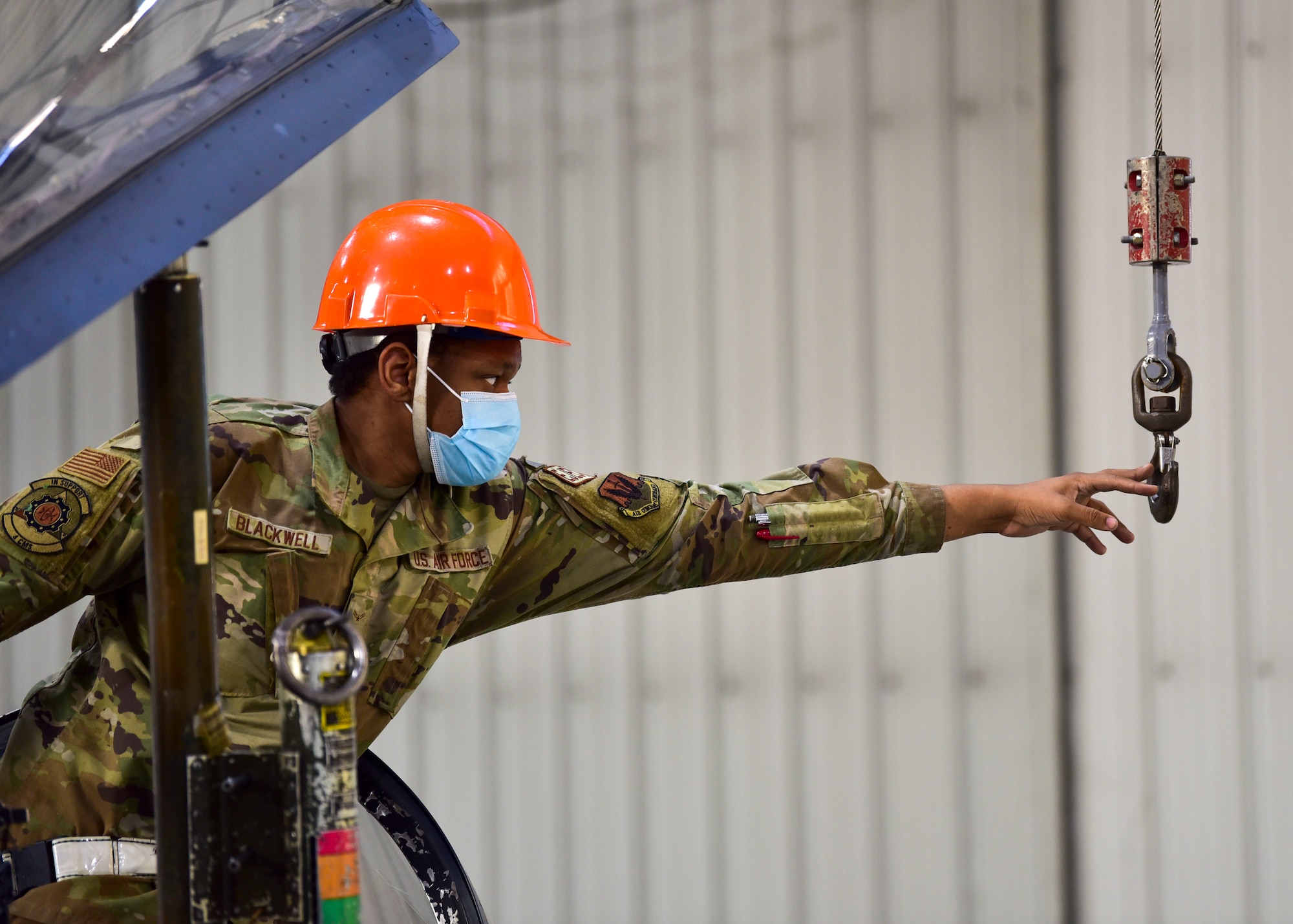 Airman 1st Class Latrell Blackwell, 4th Component Maintenance Squadron aircrew egress technician, reaches for the lifting hook of a crane at Seymour Johnson Air Force Base, North Carolina, Jan. 7, 2022.