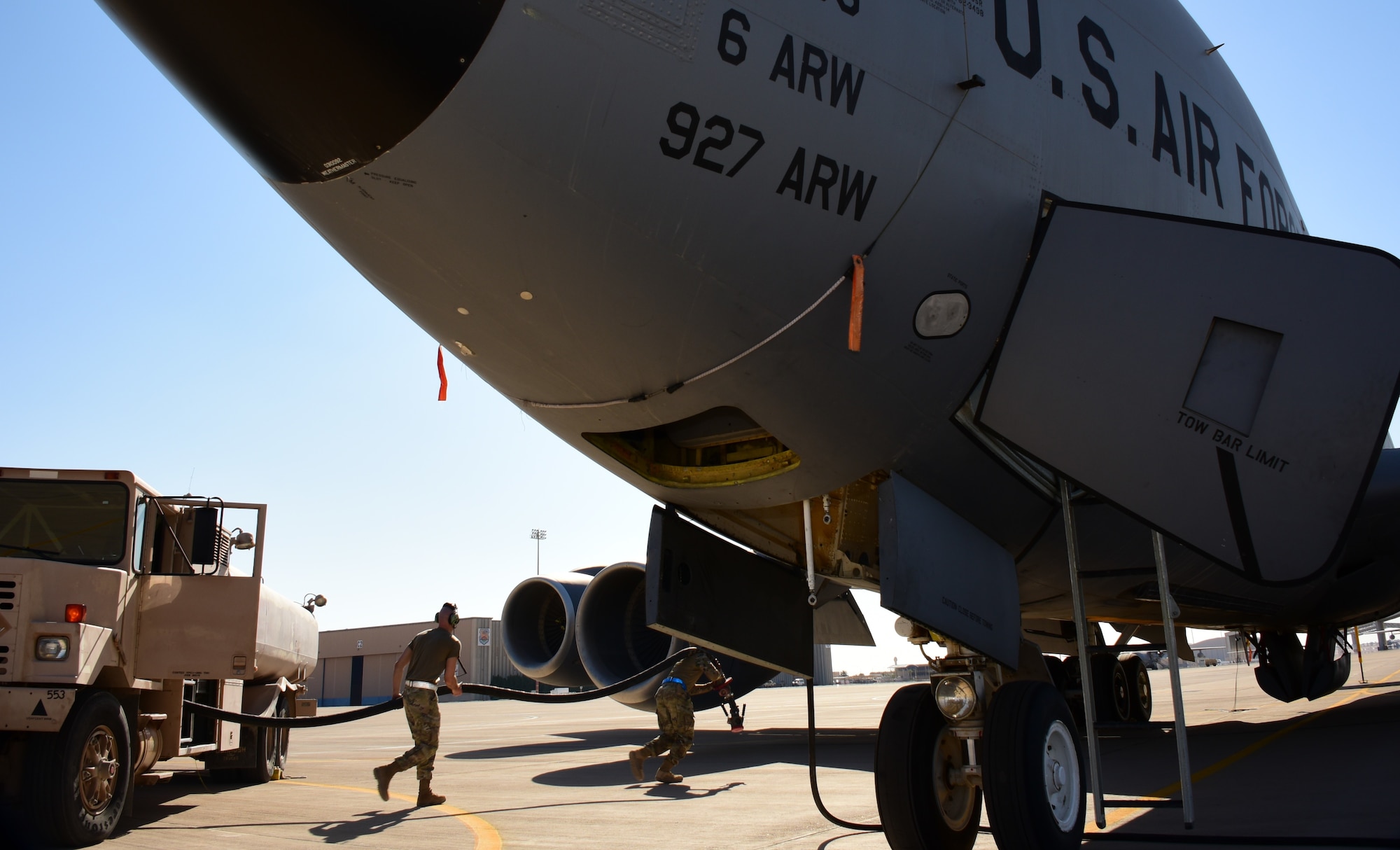 Two Airmen run a refueling hose from a truck to a KC-135 Stratotanker to refuel in on the flightline.