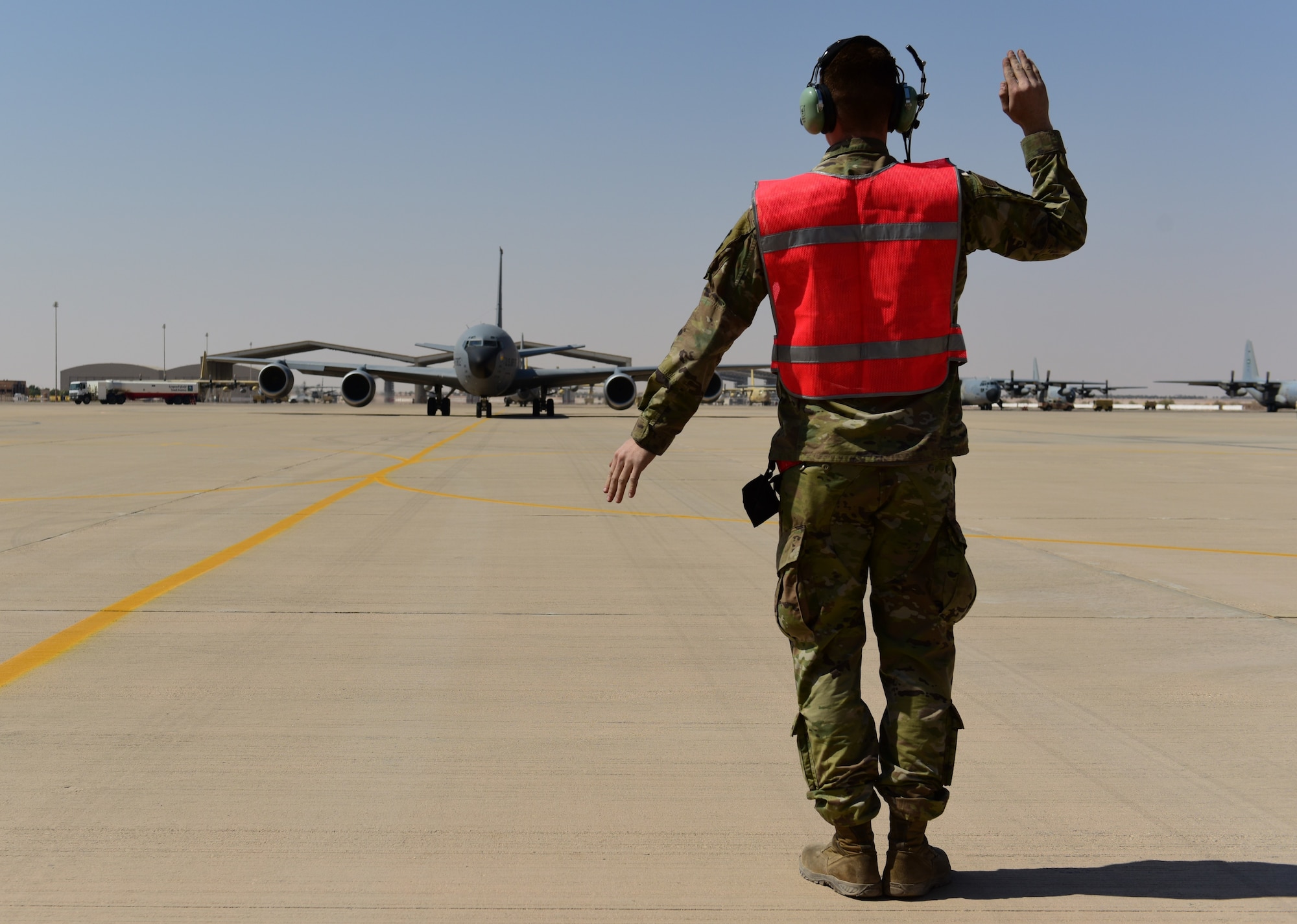 An Airman marshal a KC-135 Stratotanker aircraft on a flightline