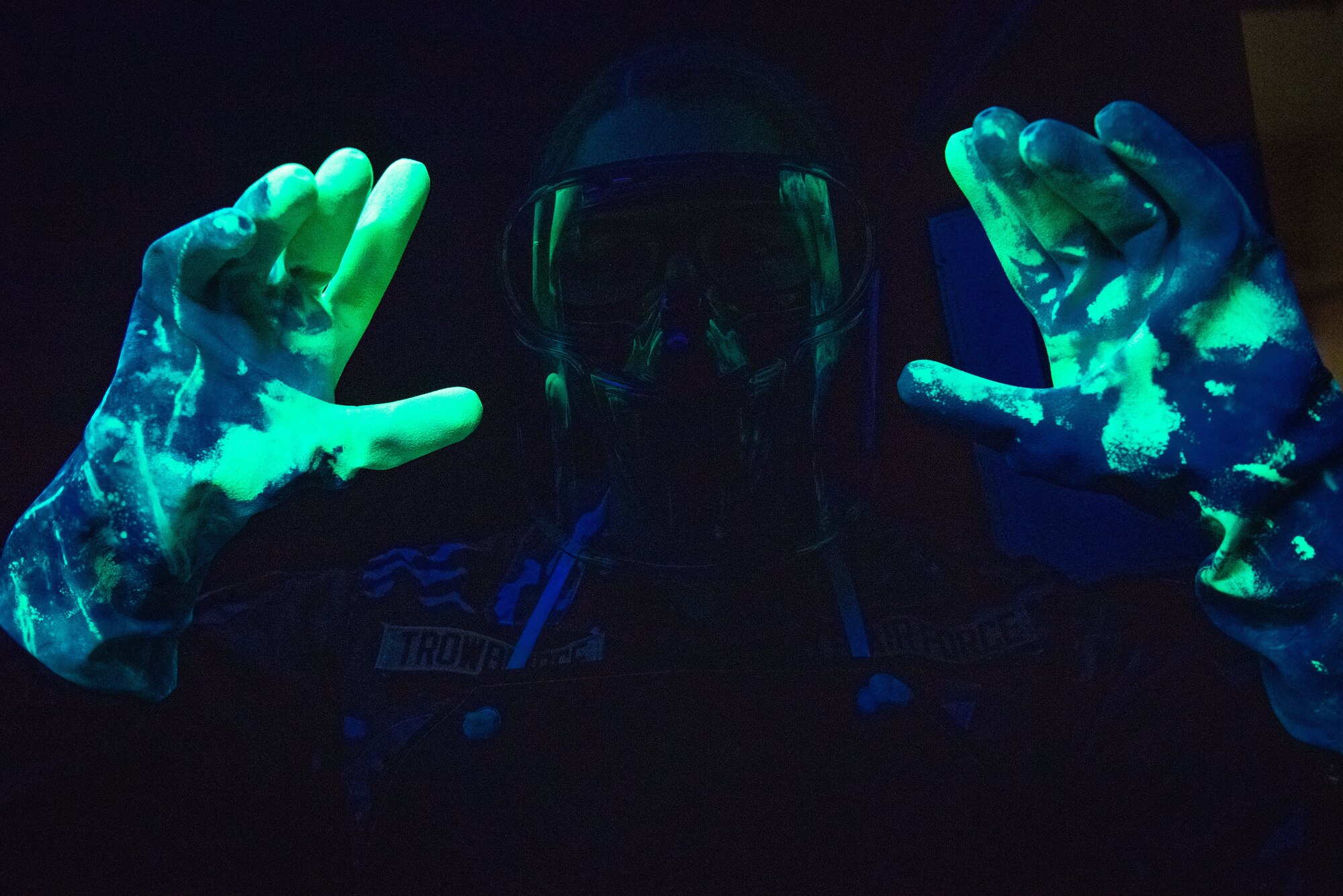Airman 1st Class Hunter Trowbridge, 51st Maintenance Squadron Nondestructive Inspection (NDI) apprentice, showcases the penetrant glow on her gloves at Osan Air Base, Republic of Korea, Feb. 17, 2022.