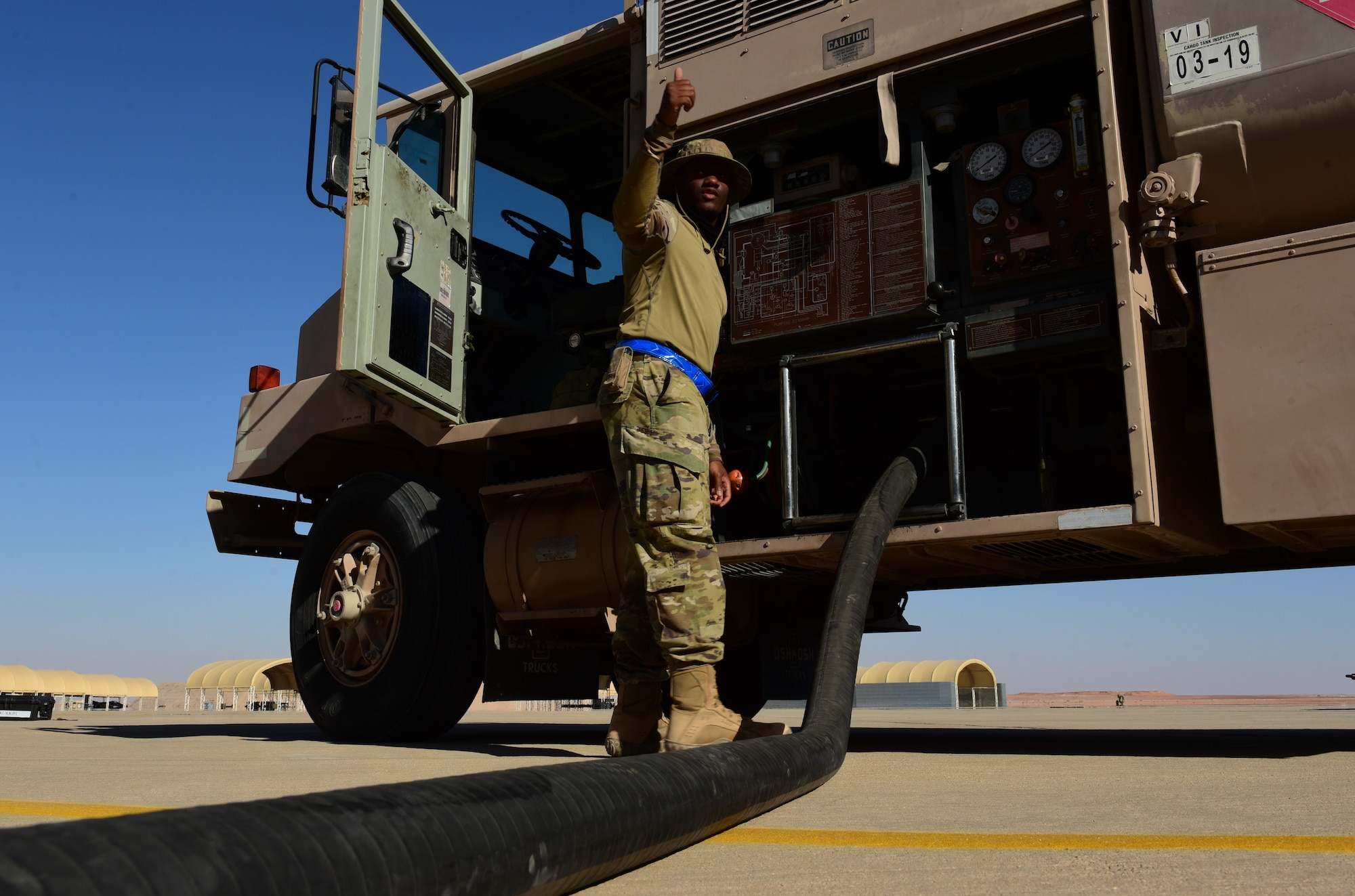 Photo of a U.S. Air Force Airman retracting a fuels hose into a fuels truck