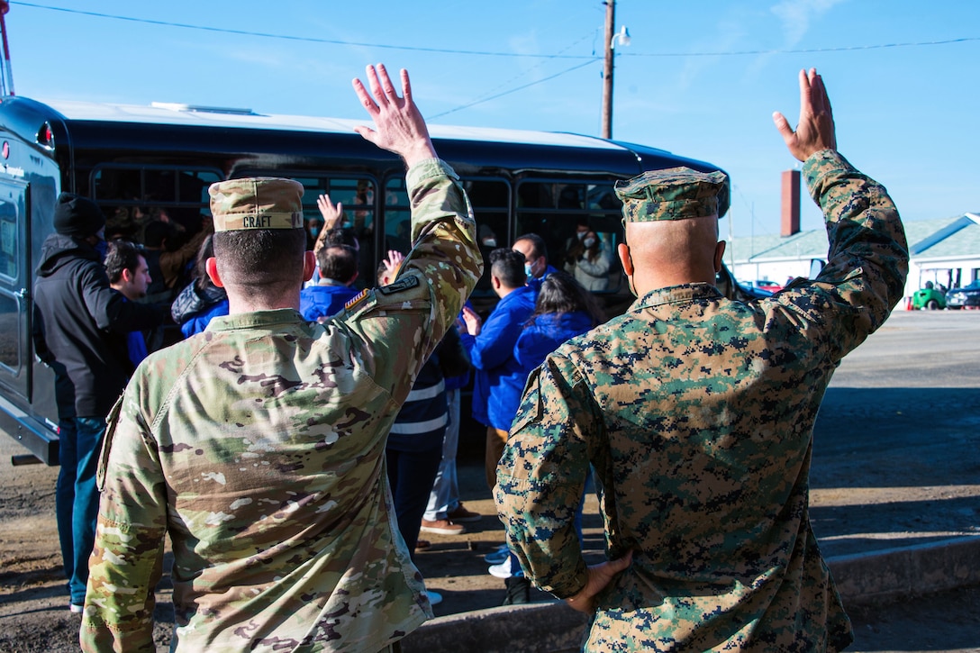 Two senior military officers wave goodbye to Afghan evacuees departing Safe Haven Pickett.