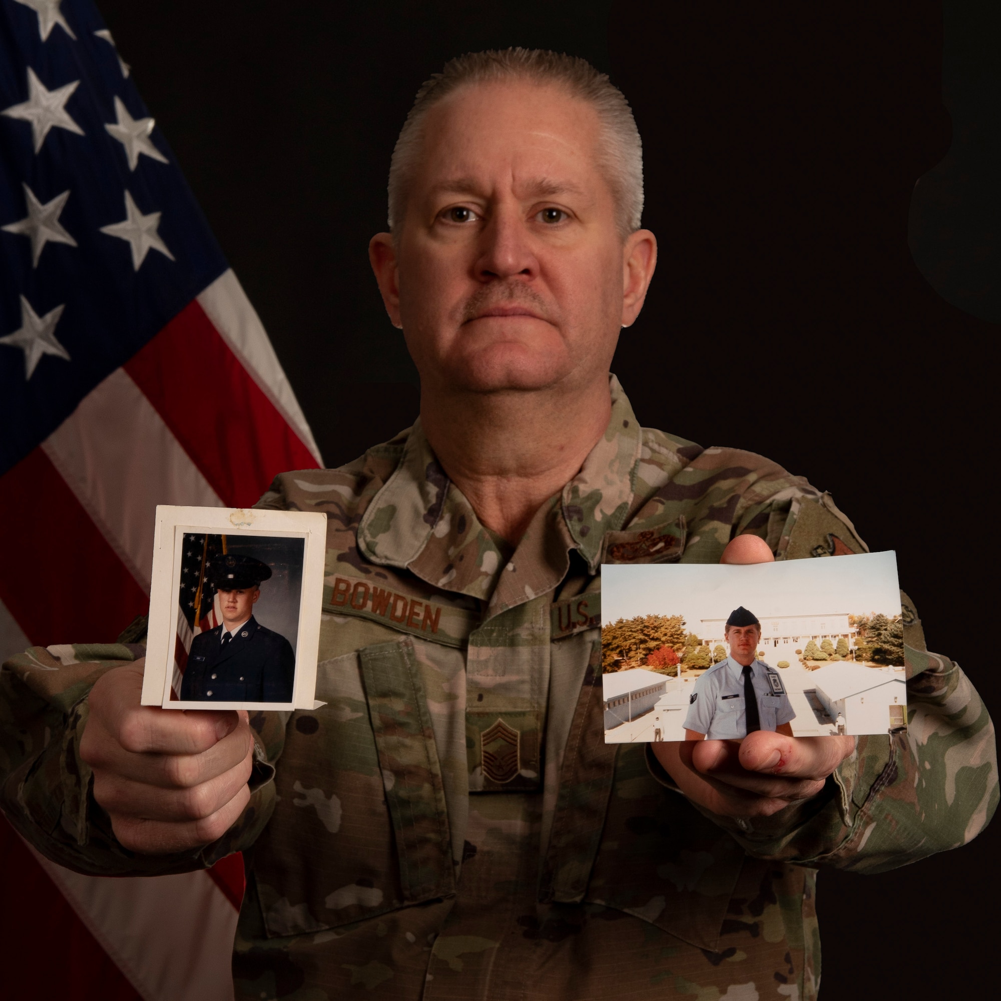 Chief Master Sgt. Michael Bowden, 434th Mission Support Group, senior enlisted leader, poses for a photo holding pictures of himself from basic training. Bowden is retiring after his quick four year enlistment to earn money for college turned into a 36 year career. (U.S. Air Force photo by Tech Sgt. Josh Weaver)
