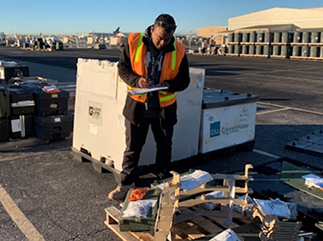 A man on a tarmac looks over some equipment on a pallet.