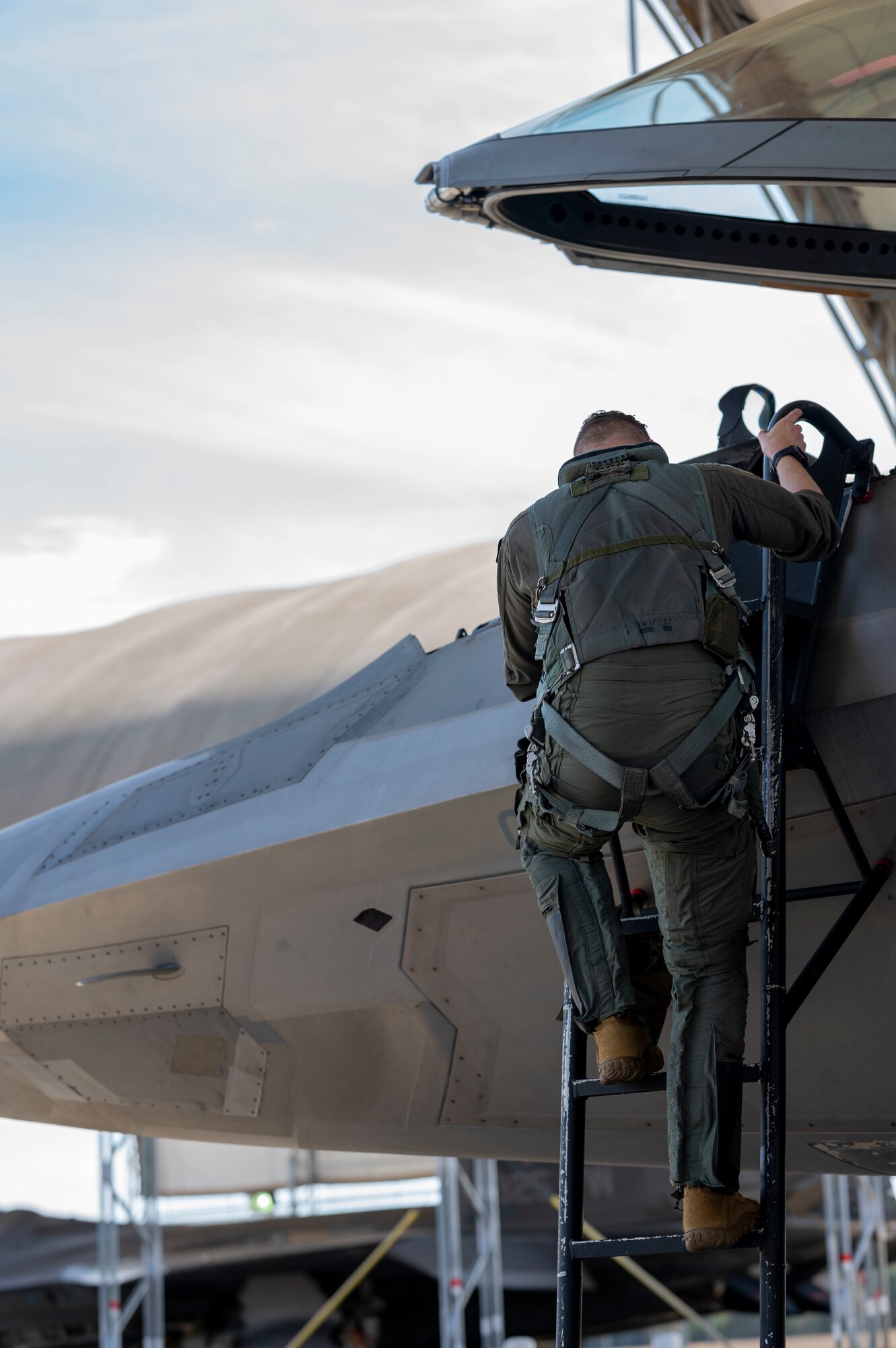 A pilot climbs into the cockpit of an F-22 Raptor
