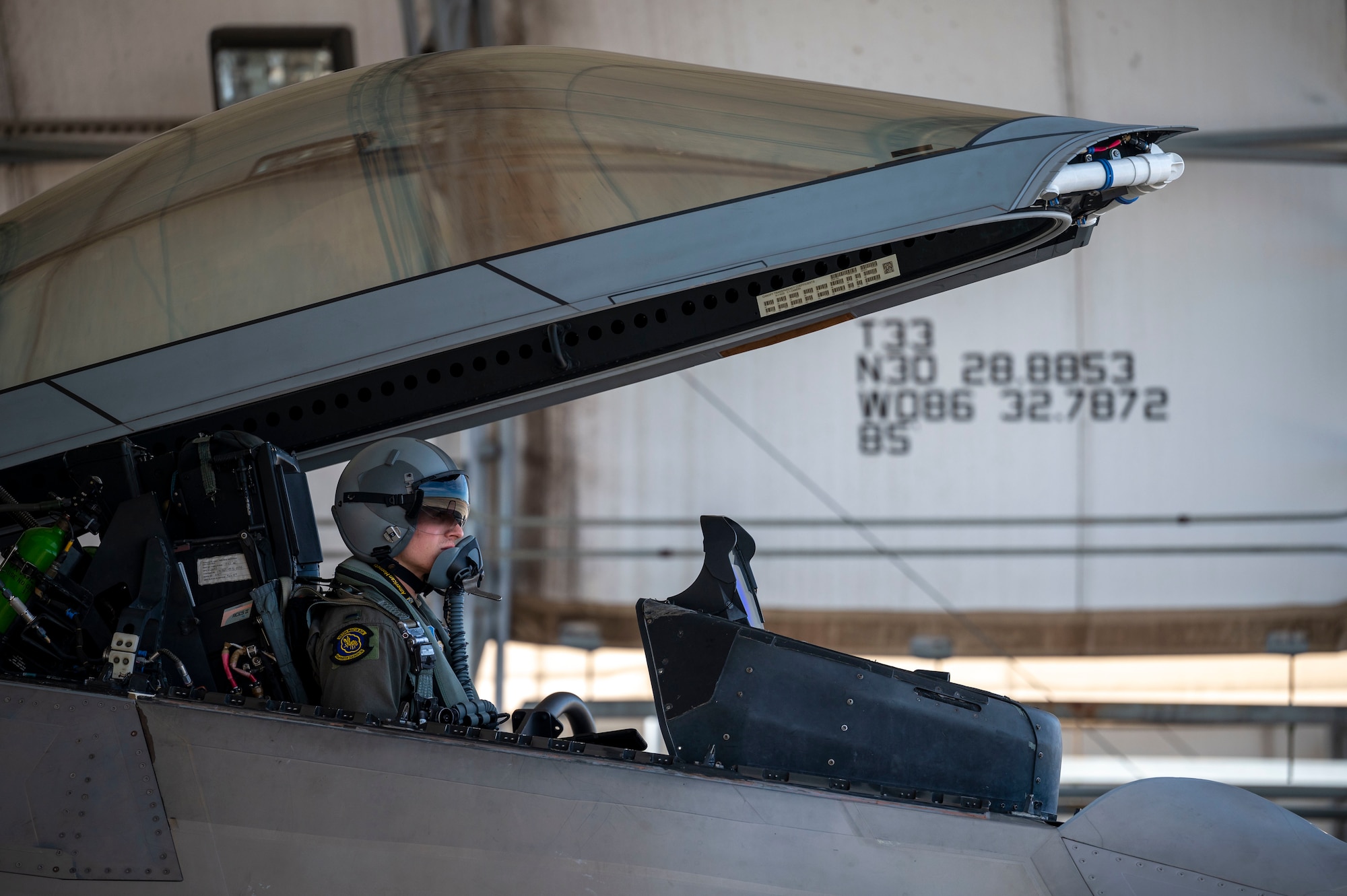A pilot sits in the cockpit of an F-22 Raptor