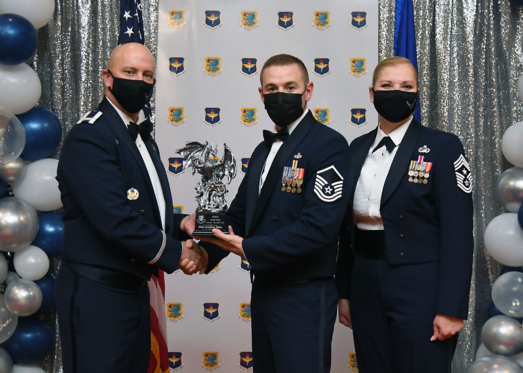 U.S. Air Force Col. William Hunter, 81st Training Wing commander, and Chief Master Sgt. Sarah Esparza, 81st TRW command chief, present Master Sgt. Jonathan Talley, 81st Security Forces Squadron logistics superintendent, with the Senior NCO of the Year award during the 81st Training Wing's 2021 Annual Awards Ceremony inside the Bay Breeze Event Center at Keesler Air Force Base, Mississippi, Feb. 17, 2022. During the ceremony, base leadership recognized outstanding Airmen and civilians from across the installation for their accomplishments throughout 2021. (U.S. Air Force photo by Kemberly Groue)