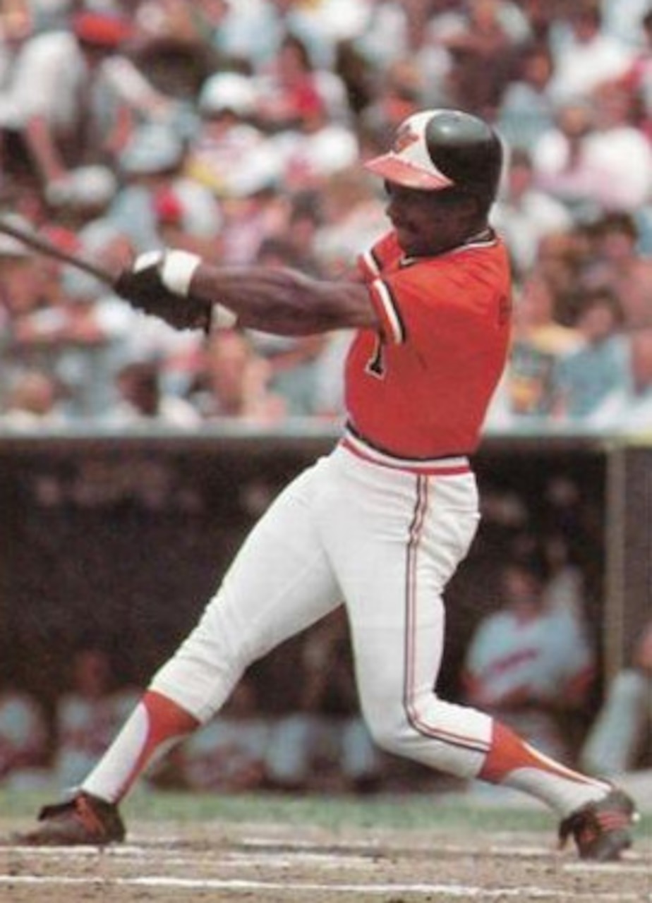 A baseball player in an Orioles uniform swings a bat.