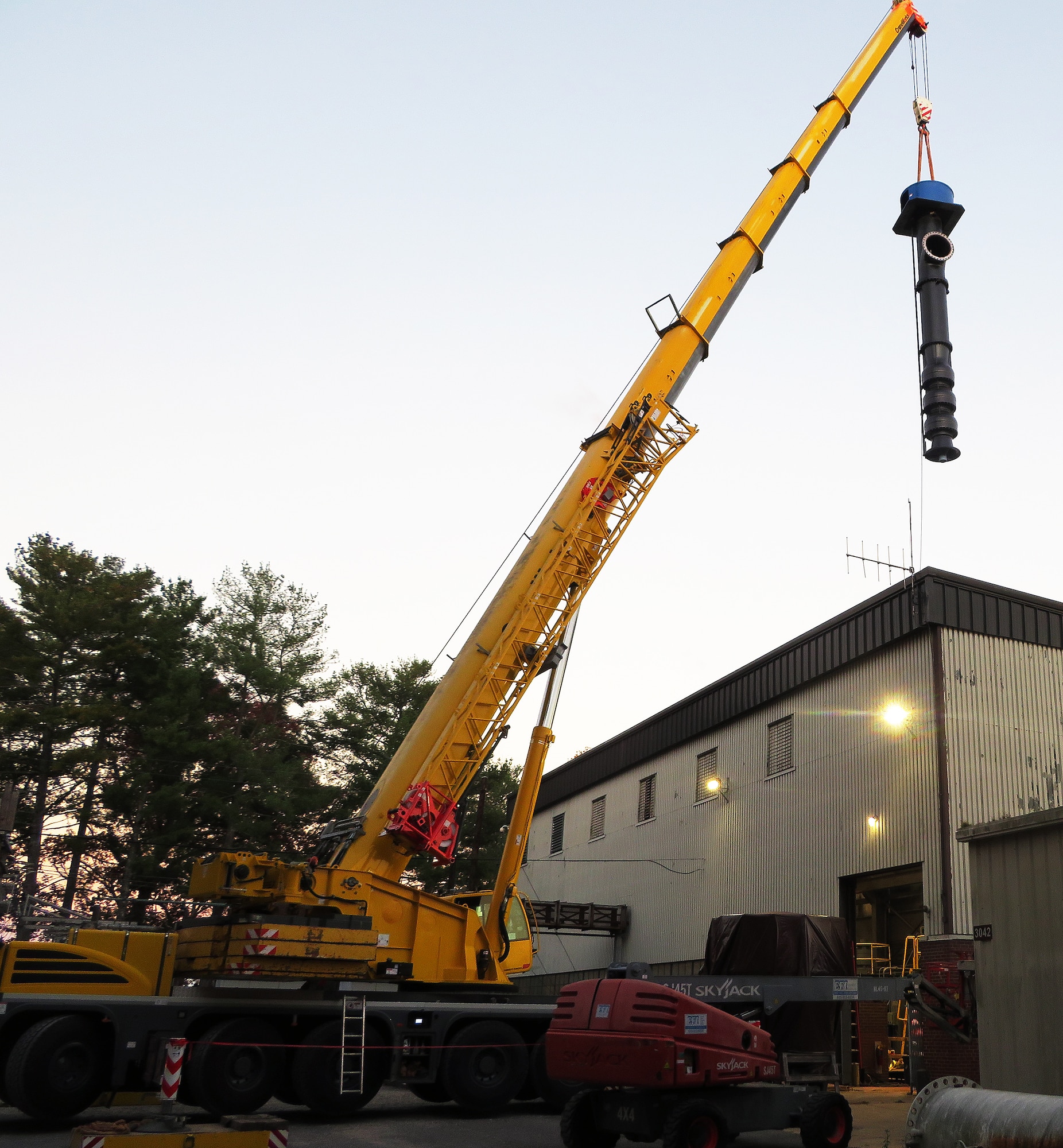 Crane lifting new pump-and-motor set above building