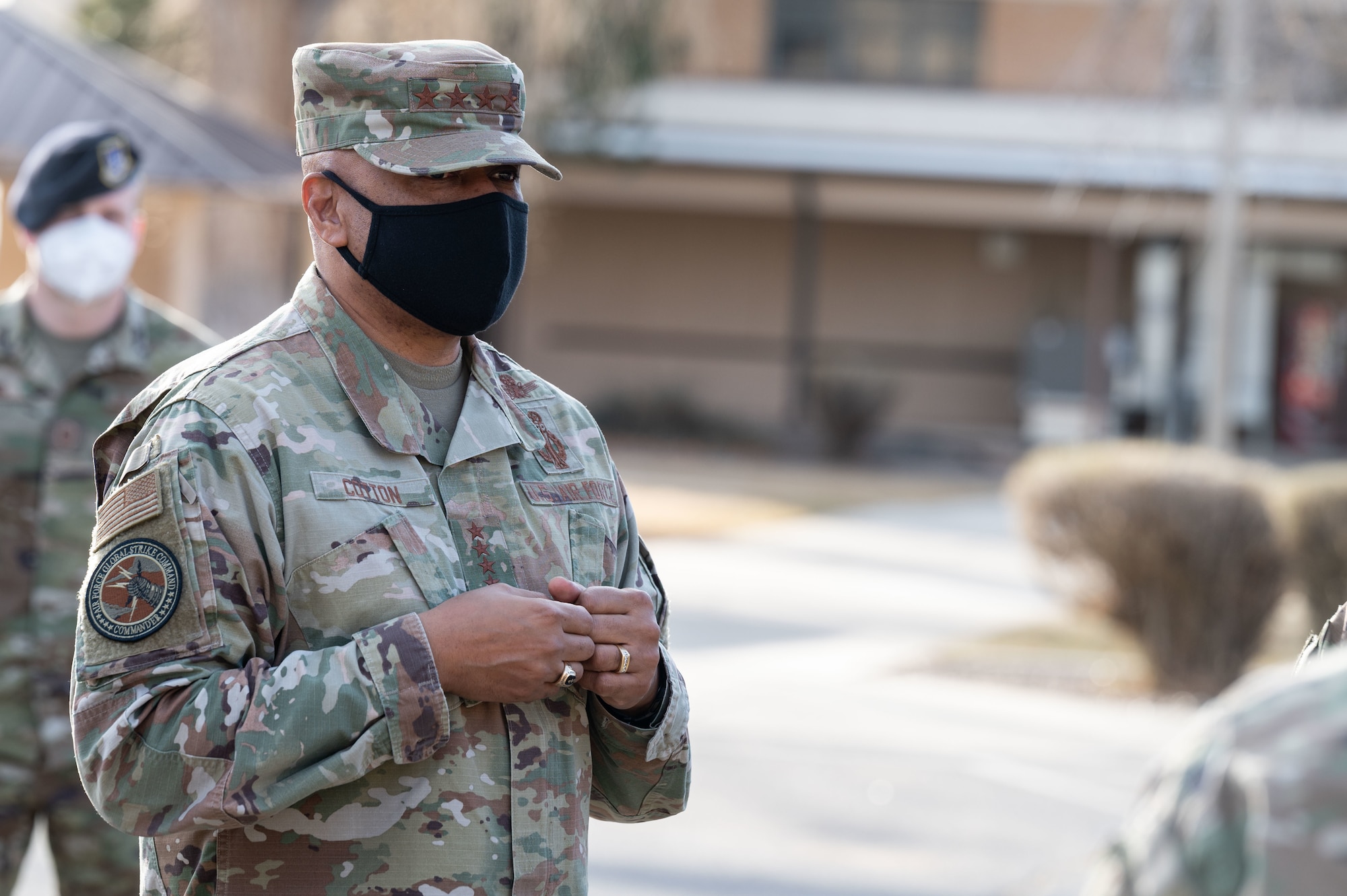 Man stands with hands in front of body.