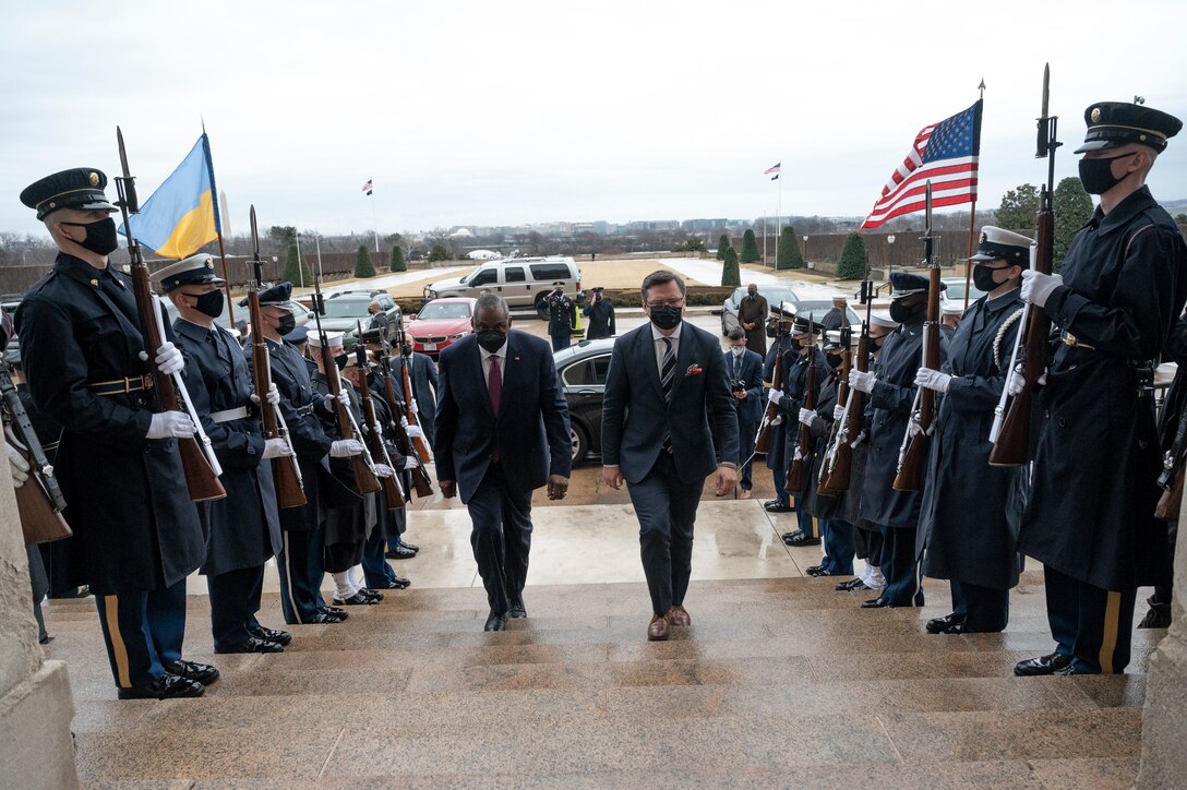 Two men walk up steps. There is an honor guard on both sides of the steps.