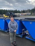 A woman poses in front of three garbage cans.