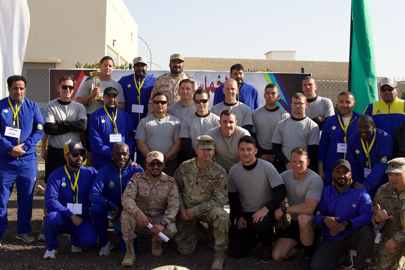 Soldiers and foreign troops pose for a group shot outside.