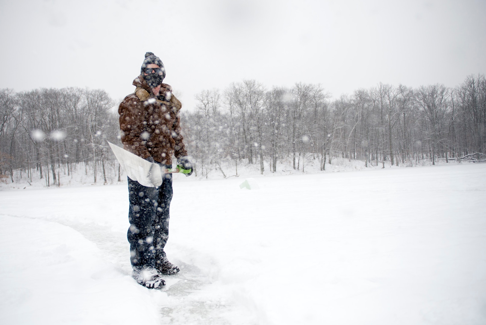 Service member in winter gear shovels snow