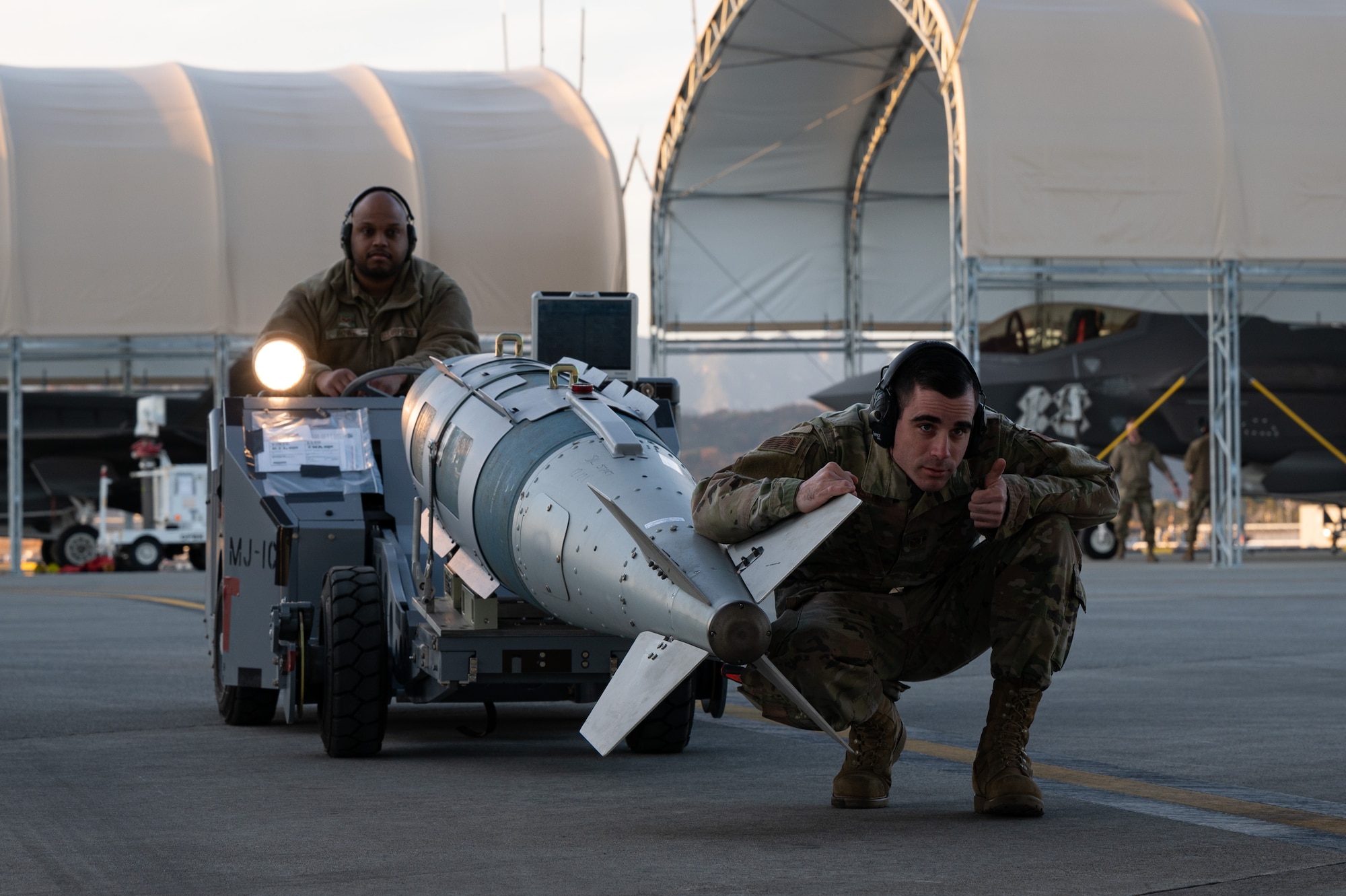 U.S. Air Force Senior Airman Kedrick Powe, left, a 354th Air Expeditionary Wing (AEW) weapons load crew member, and Staff Sgt. Joshua Bussard, a 354th AEW weapons load crew chief, prepare to install an inert GBU-31 bomb on an F-35A Lightning II during Operation Iron Dagger on Marine Corps Air Station Iwakuni, Japan, Dec. 9, 2021.
