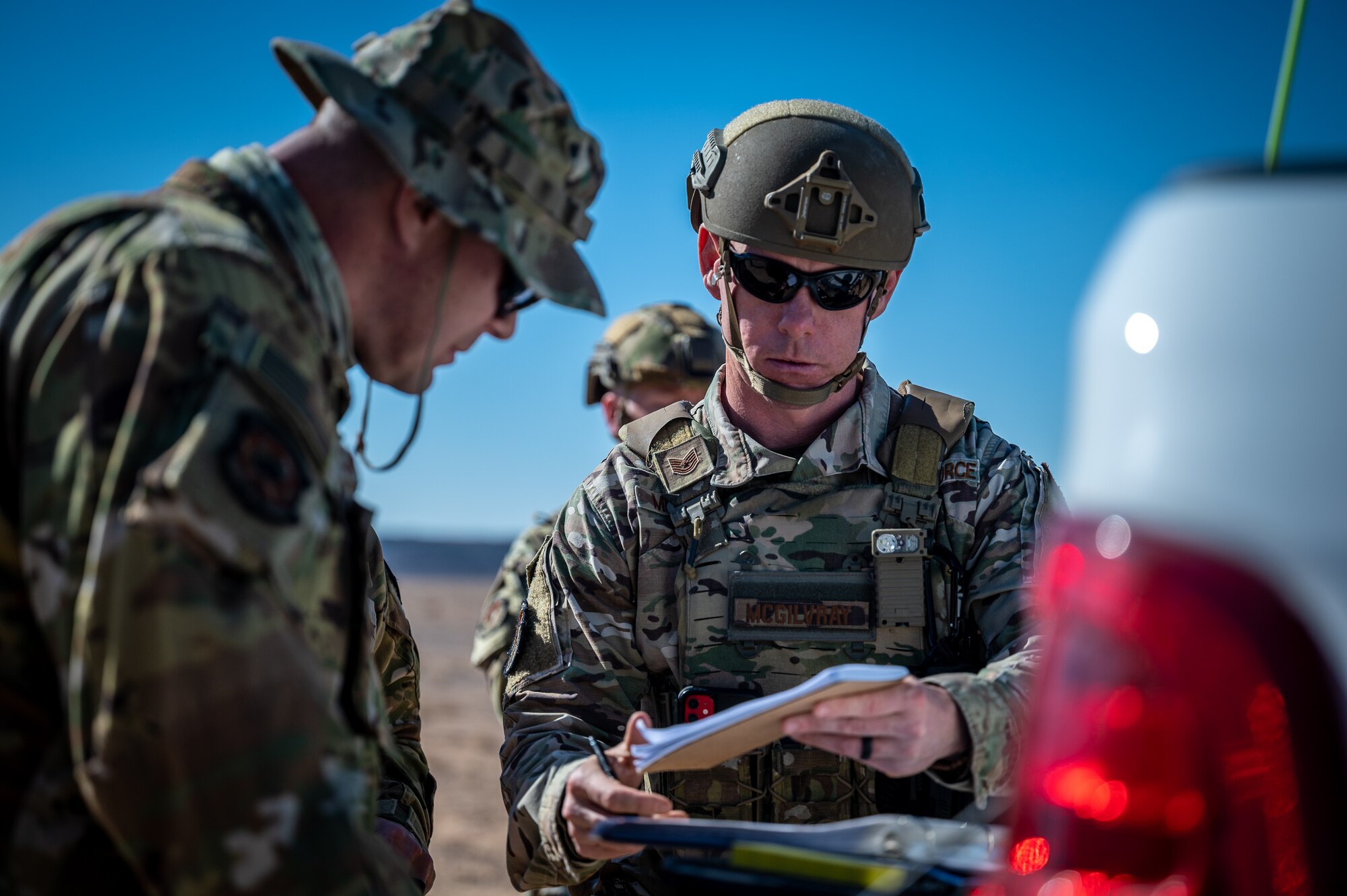 Senior Master Sgt. Joshua Cameron, 332d Expeditionary Wing Fire and Emergency Services fire chief and incident commander, works with Tech. Sgt. Brian McGilvray, 332d Expeditionary Security Forces Squadron team member, to establish an entrance control point during a counter small unmanned aircraft system training exercise in Southwest Asia Feb. 12, 2022. The intent of the small unmanned aircraft system, non-friendly drone detection training is to bring multiple agencies together to exercise the joint effort of protection of personnel and property, risk assessment, communication, coordination, develop and execute a plan of attack, hazard mitigation, scene safety, and evidence collection with security forces, explosive ordnance disposal and the incident command center. (U.S. Air Force photo by Master Sgt. Christopher Parr)