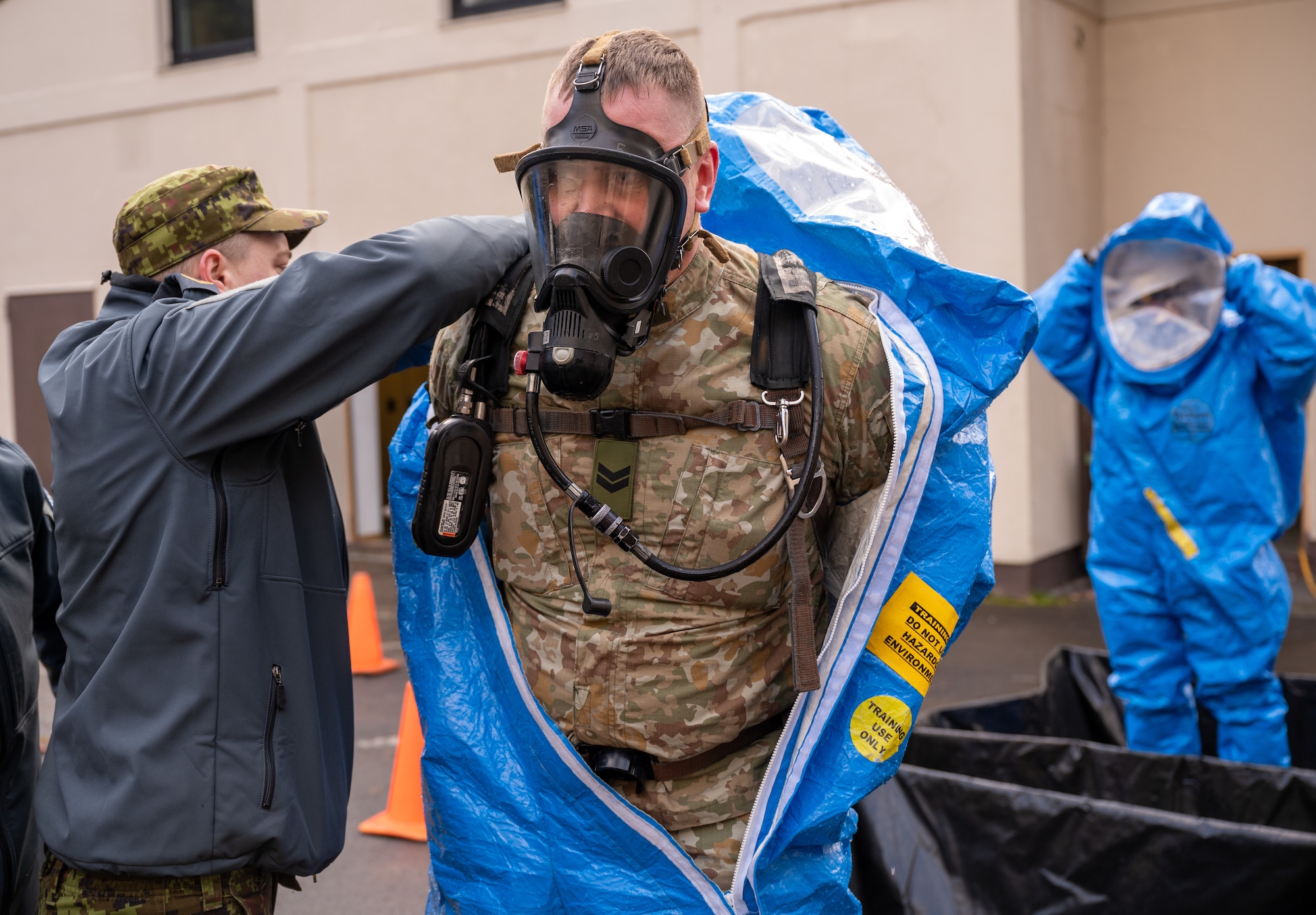 A person helping another person out of a HAZMAT suit.