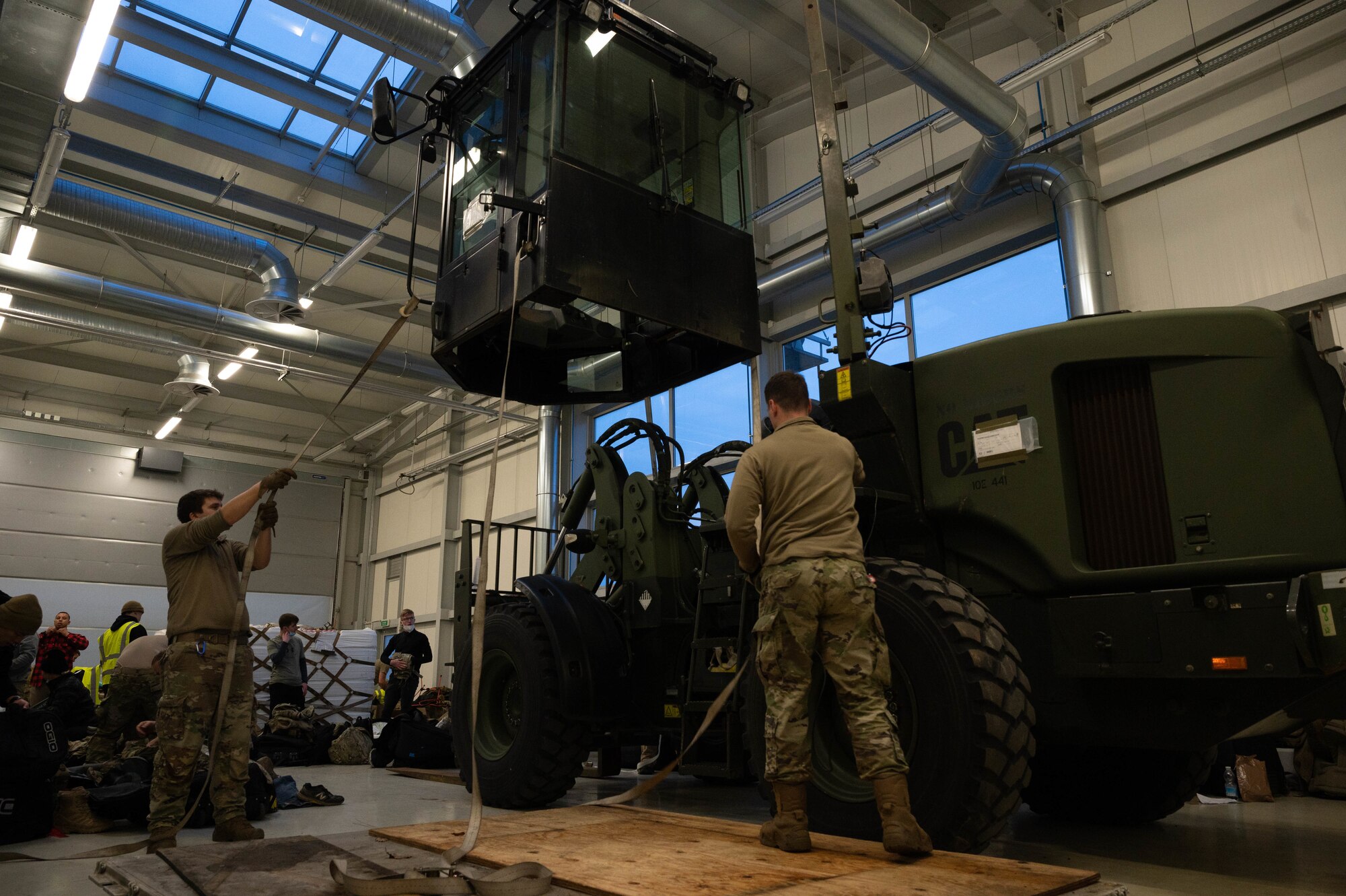 Airmen place a cab on top of a 10K all-terrain forklift.