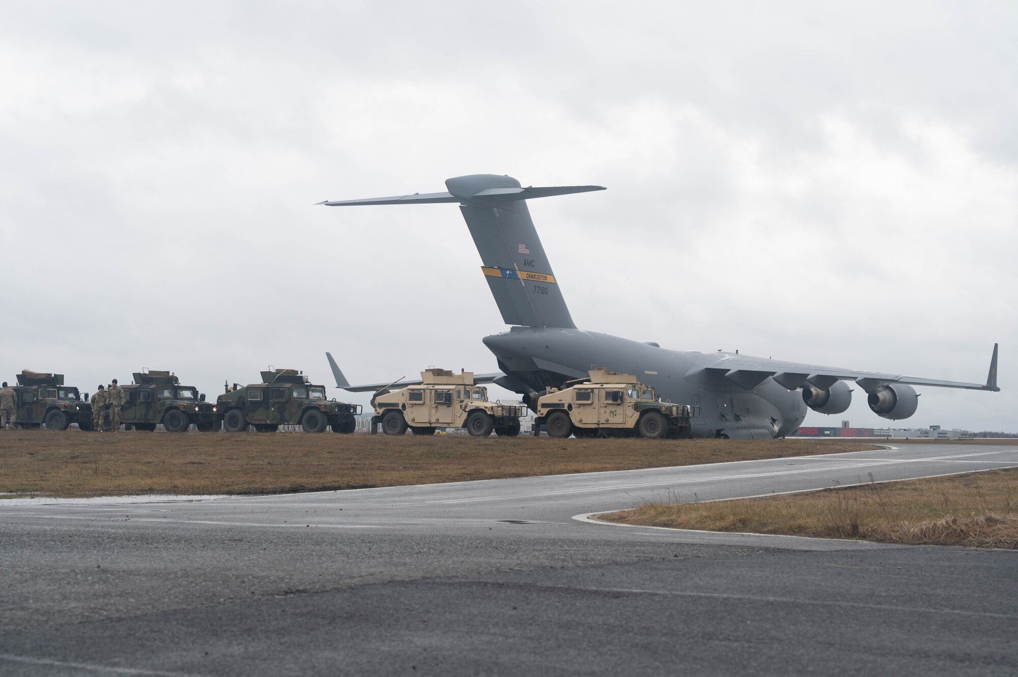 U.S. Army Humvees line up near a C-17 Globemaster III aircraft.