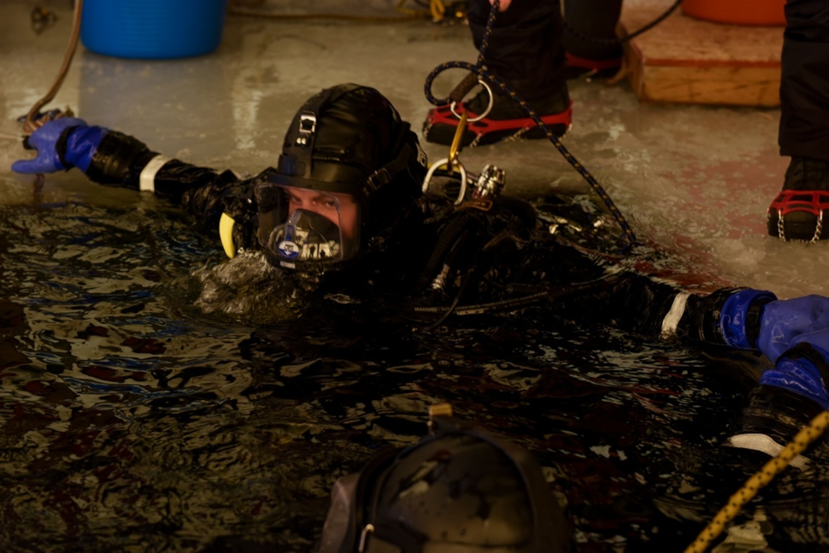 U.S. Coast Guard Petty Officer 2nd Class Samuel Wilson, a student in the Cold Water Ice Diving (CWID) course, resurfaces on Ferrell Lake, located on Camp Ripley, Feb. 3, 2022. Divers hold onto the edge of the ice until instructed to exit the water. (U.S. Coast Guard photo by Petty Officer 3rd Class Jessica Fontenette)