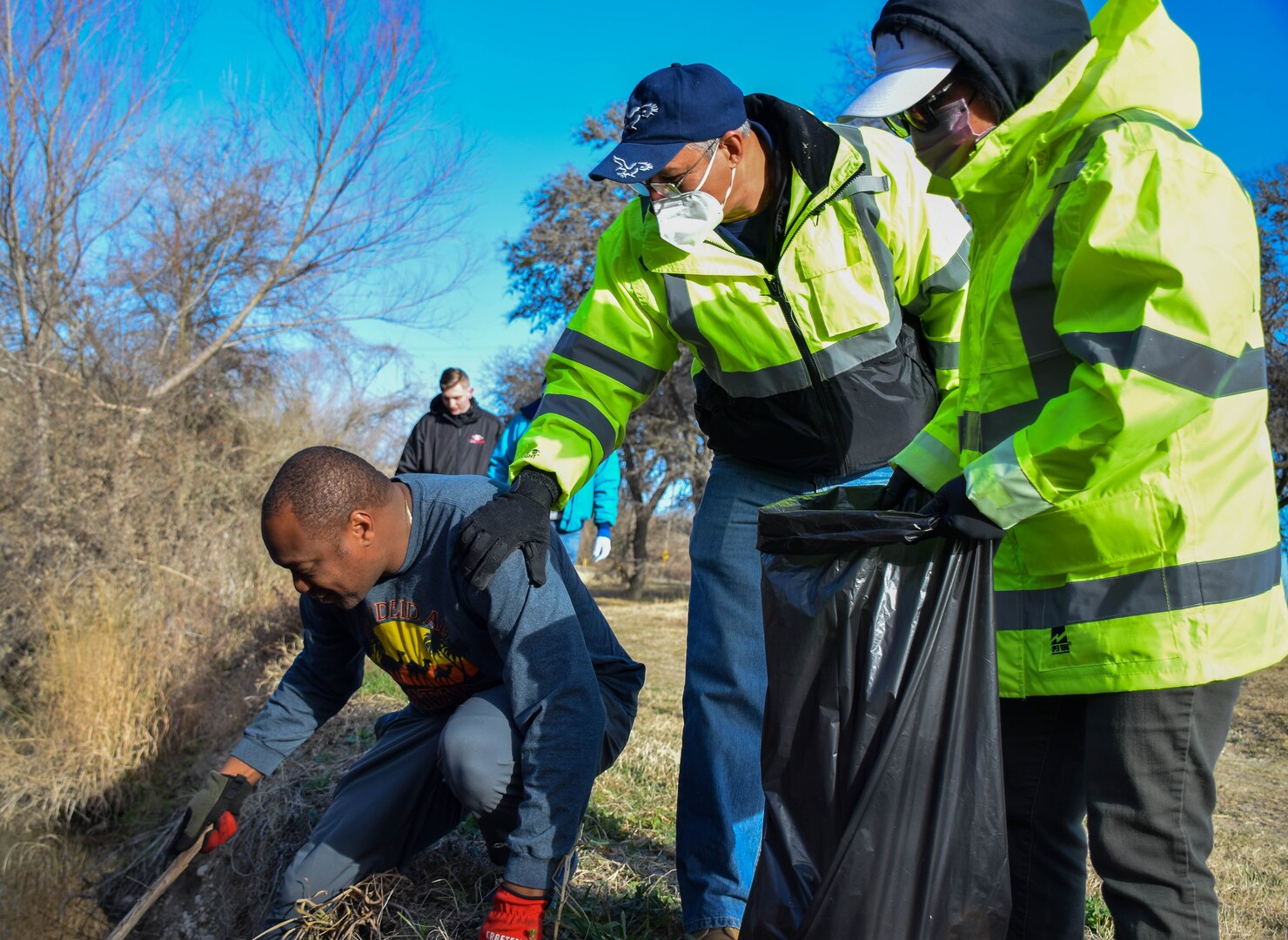 Master Sgt. Bryan Boyd, 733rd Training Squadron military training leader, removes trash from Leon Creek at Stillman Park with the assistance of Amilkar Crompton and Maya Bernstein, 502nd Logistics Readiness Squadron motor vehicle operators, at Joint Base San Antonio-Lackland, Texas, Feb. 18, 2022. The cleanup was a joint initiative coordinated by the 502nd Installation Support Group to remove garbage and debris from on-base parks and waterways. (U.S. Air Force photo by Airman Mark Colmenares)