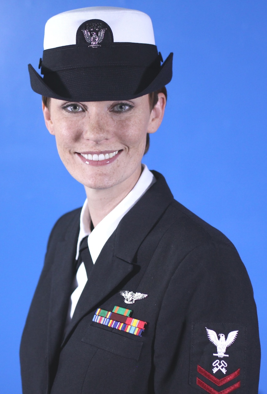 A sailor in uniform smiles for a photo.