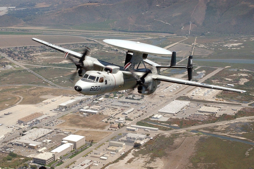 An aircraft flies over buildings.