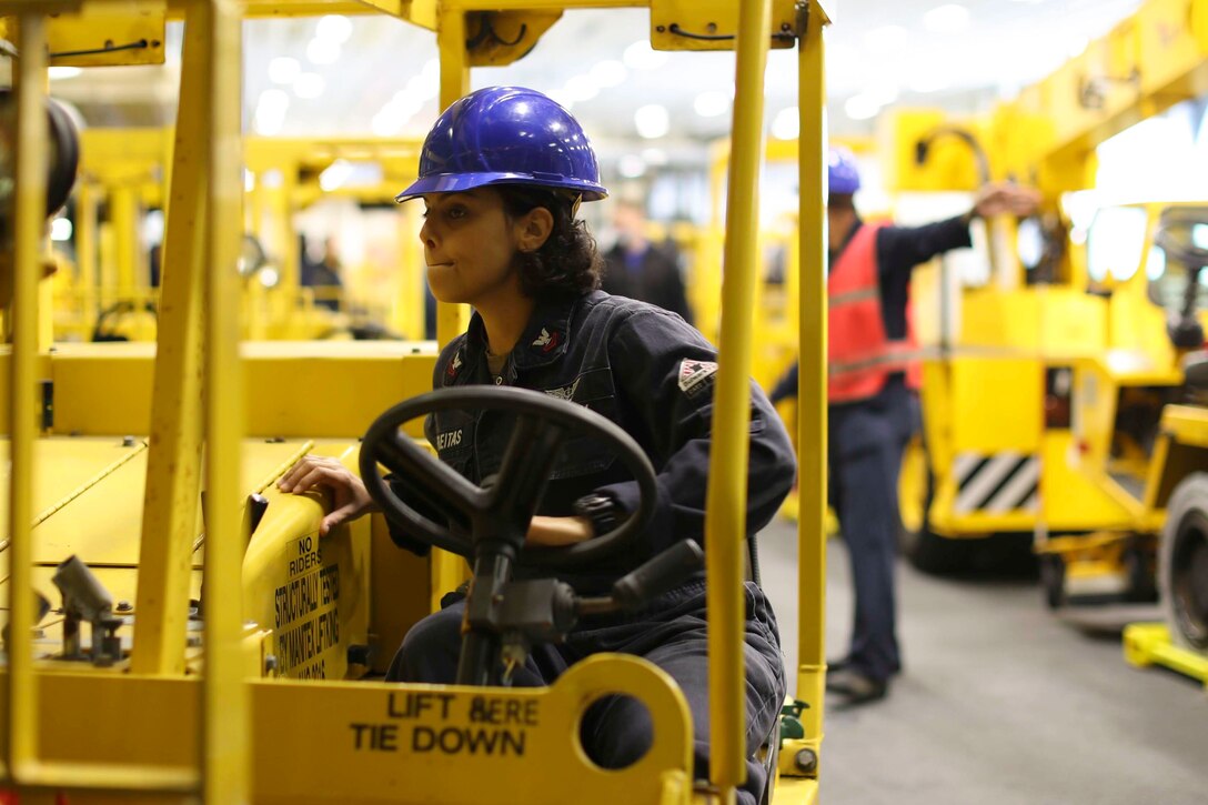 A sailor uses a forklift aboard a ship at sea.