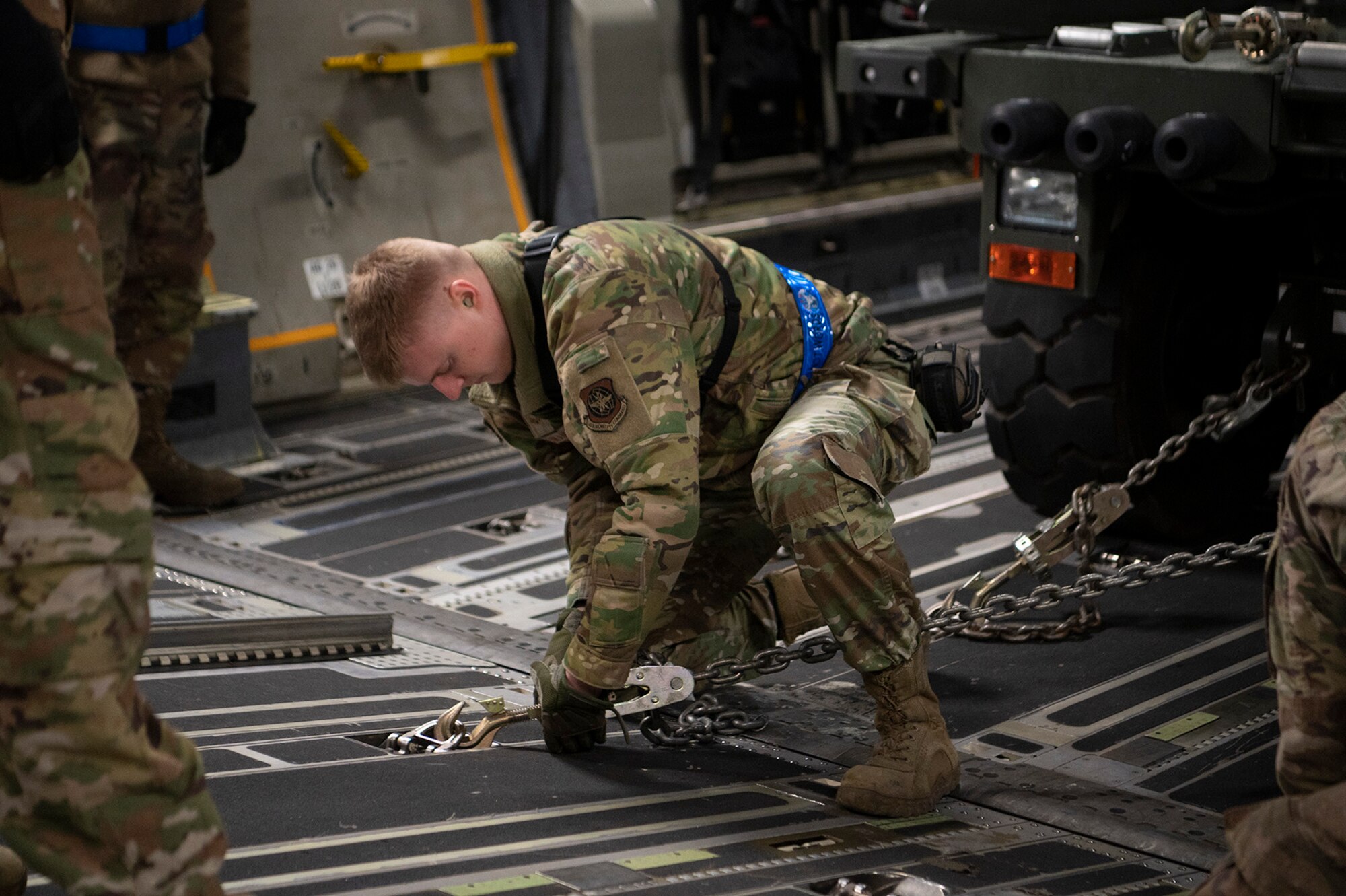 man chains cargo to the floor of a plane