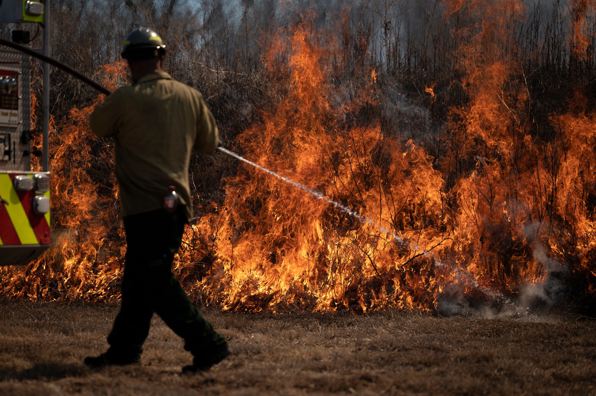 A firefighter puts out a controlled fire with a hose.