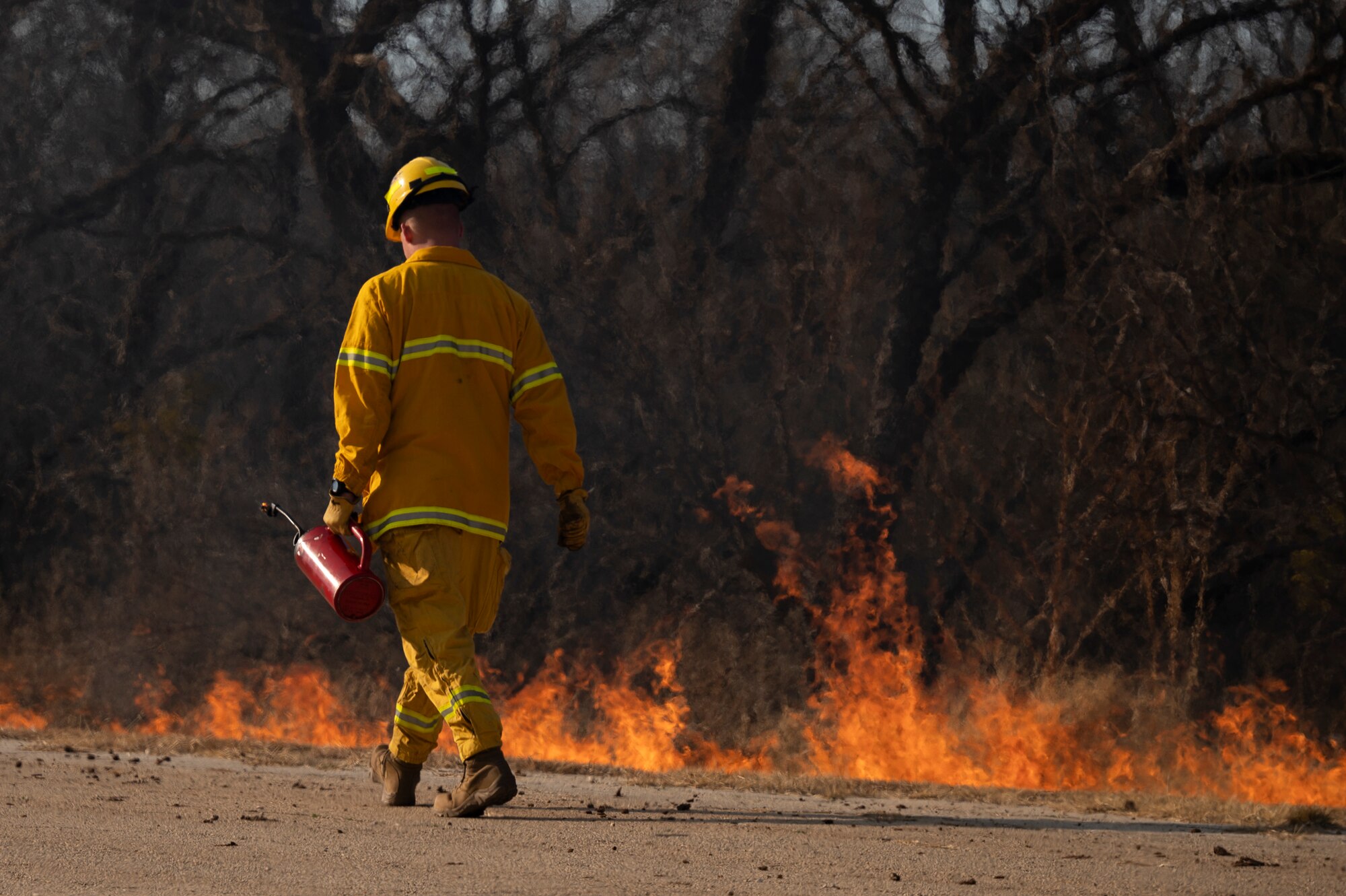 An Airman walks alongside a controlled fire.