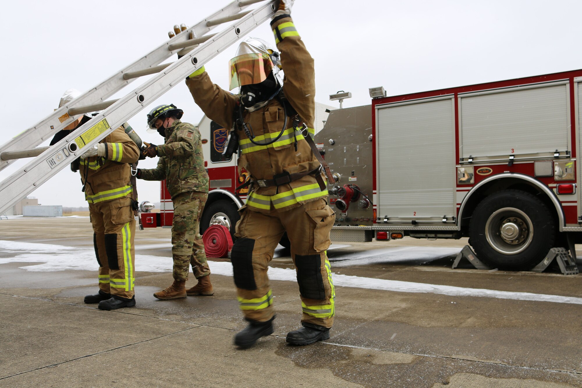 Firefighters raise a ladder to practice functional movement in protective gear during joint firefighter integrated response ensemble training, Feb. 13, 2022. Firefighters in the 445th Civil Engineer Squadron suited up in multiple pairs of pants, heavy-duty gloves and special helmets then worked through a functional obstacle course which incorporated traditional duty tasks like dragging a hose in a kneeling position, raising ladders, squatting, pivoting and carrying objects.